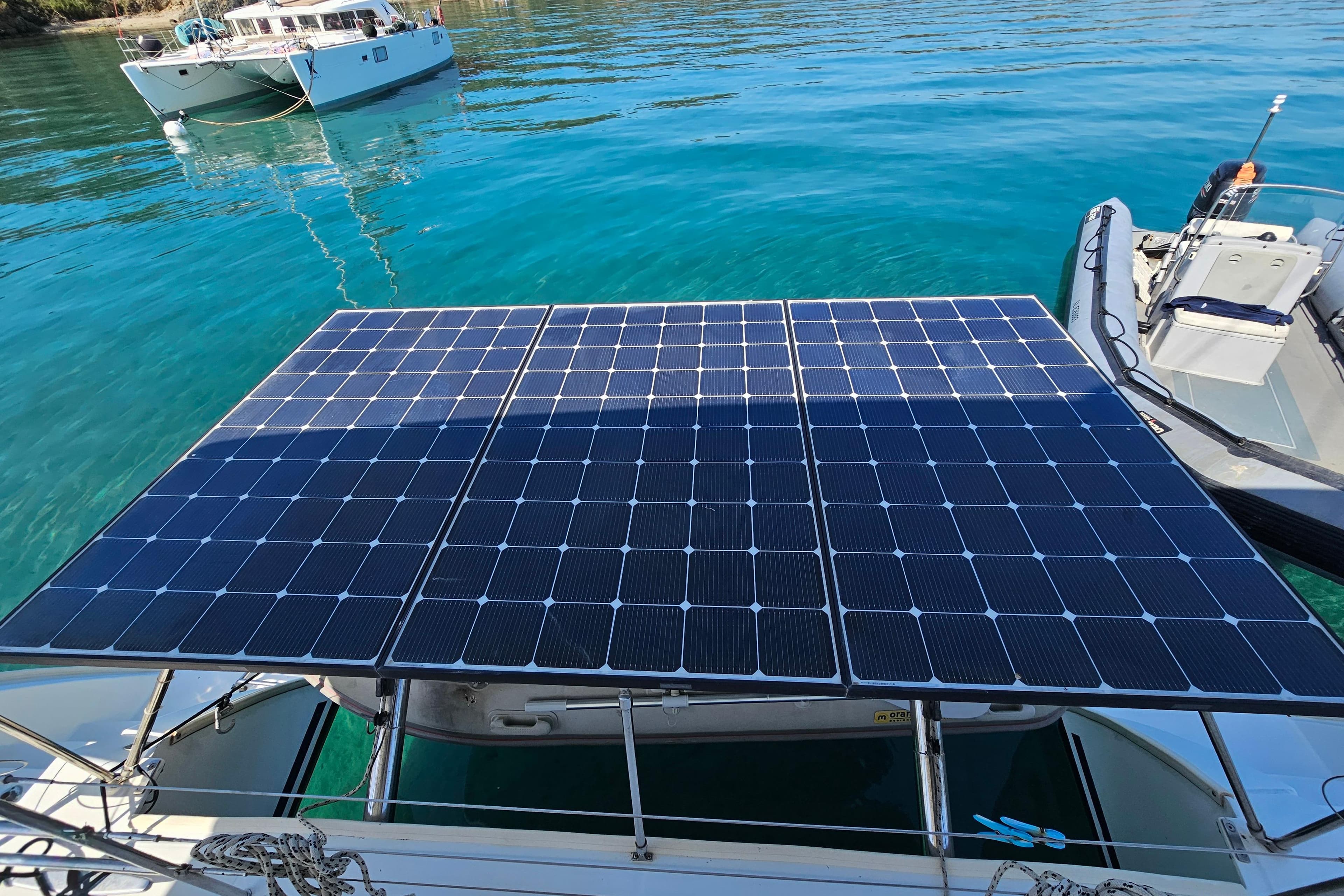 Lagoon 420 catamaran with solar panels on deck, anchored in clear blue water.