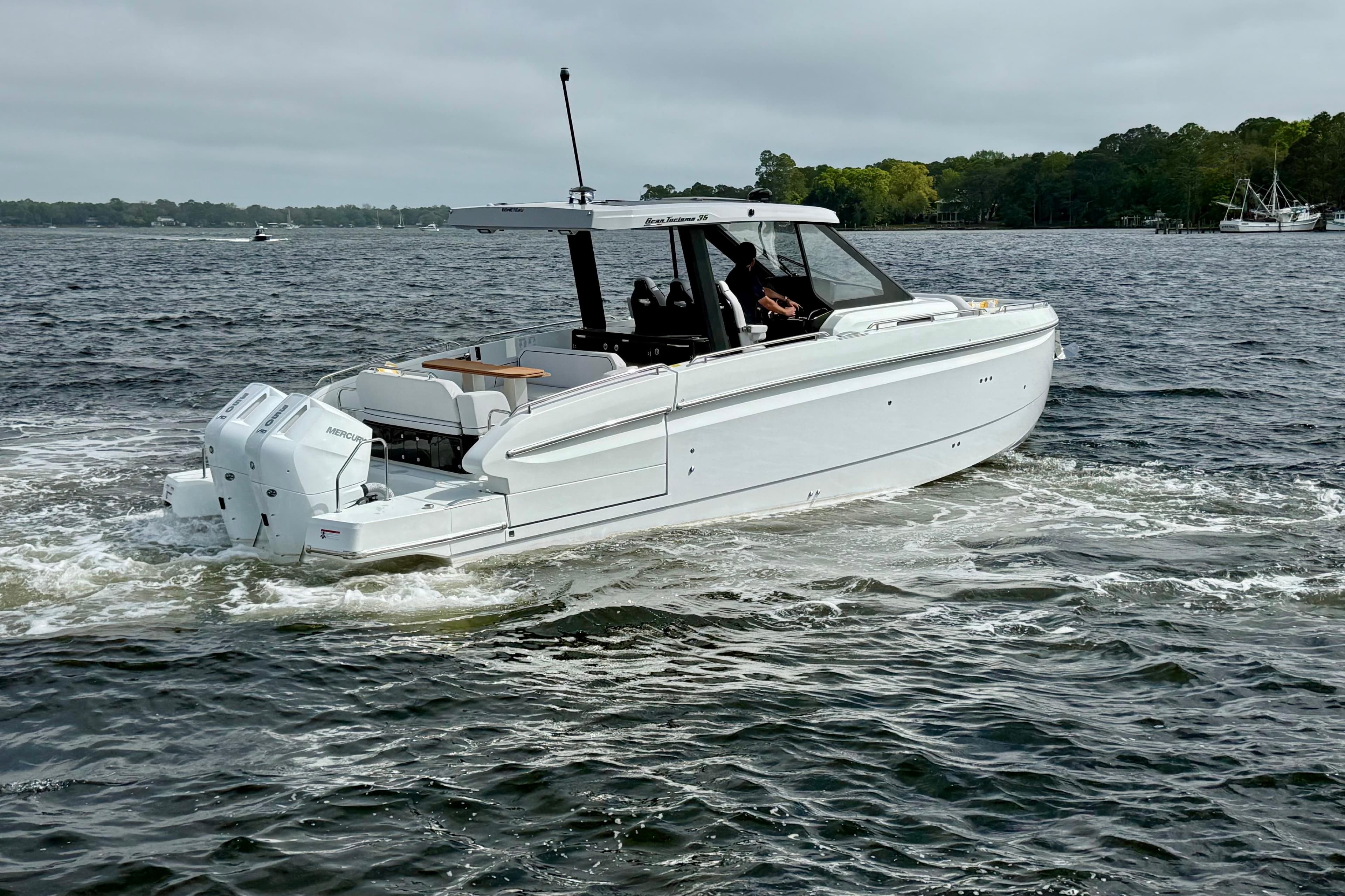 2026 Beneteau Gran Turismo 35 cruising on a lake with lush green shoreline.