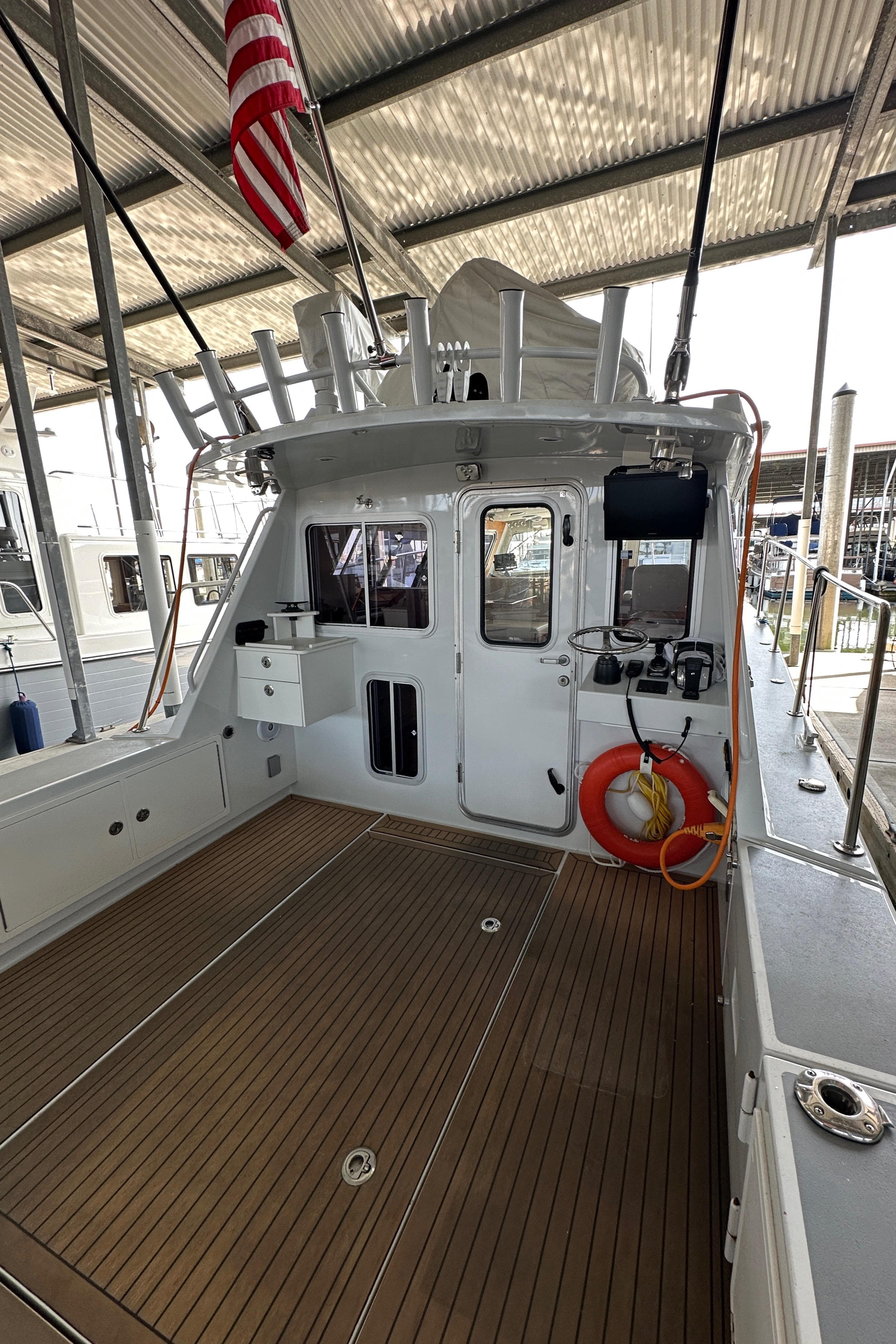 2020 Coastal Craft 33 ProFish boat with spacious deck, docked under a metal canopy.
