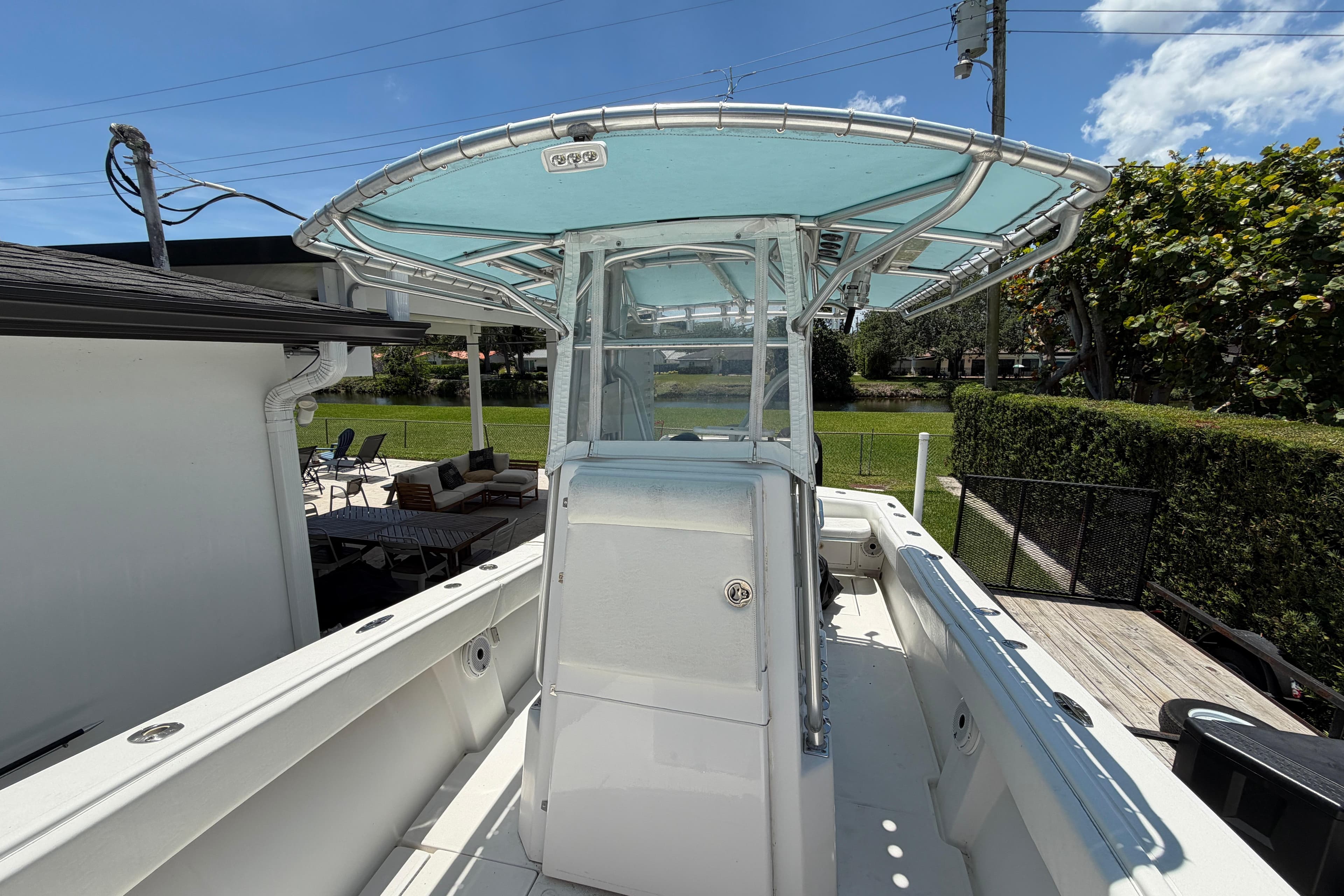 2005 Competition 25 boat with T-top, docked near a house, under clear blue skies.