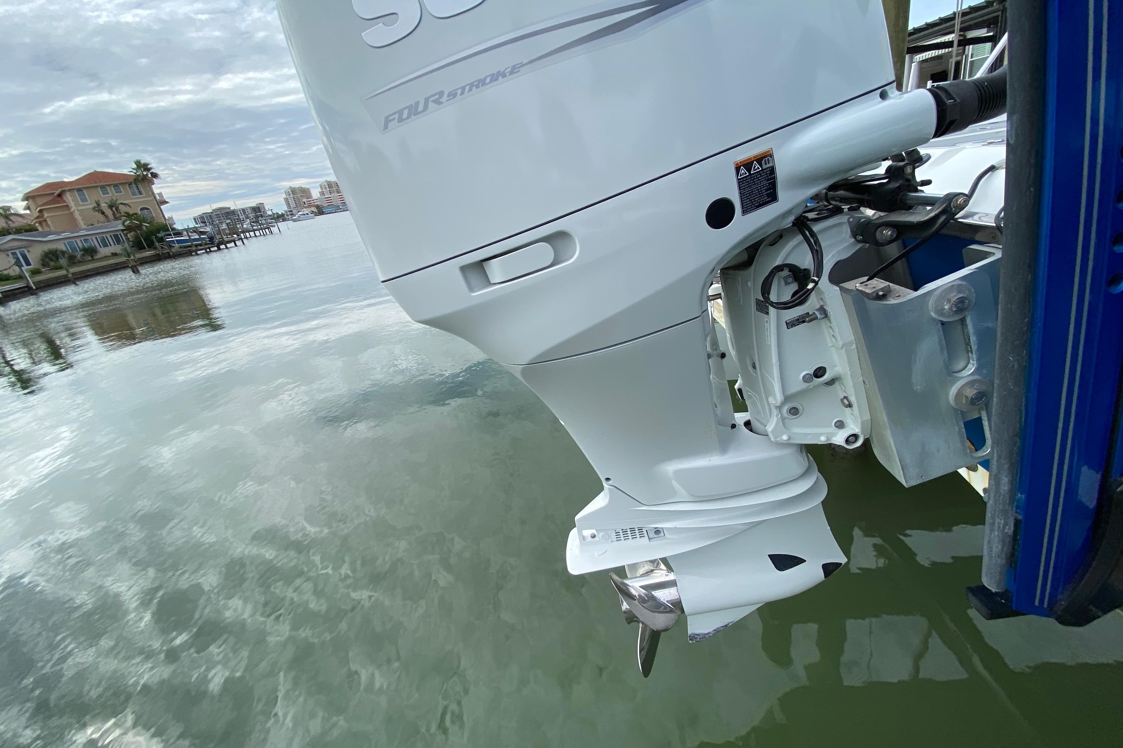Outboard motor on a 2004 Palmetto 22 Excursion boat, docked by waterfront homes.