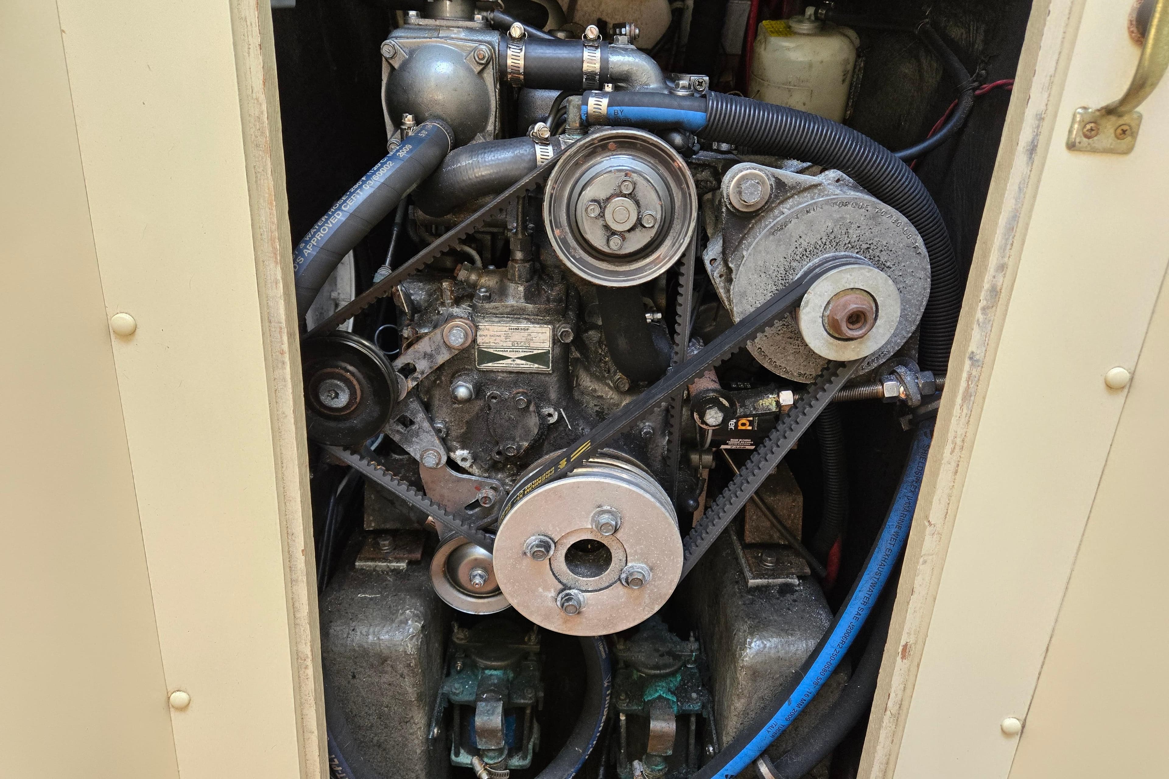 Engine compartment of a 1989 Pearson 37-2 sailboat, showcasing belts and pulleys.