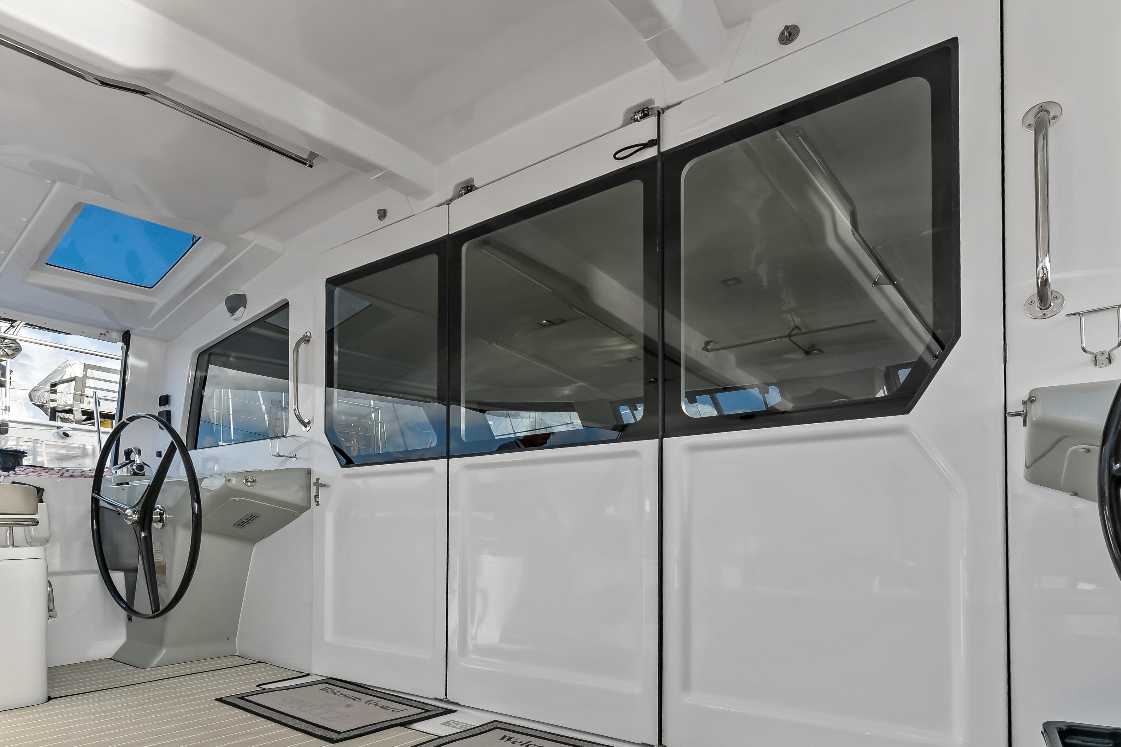 Interior view of 2026 Seawind 1370 yacht cockpit with steering wheel and glass doors.