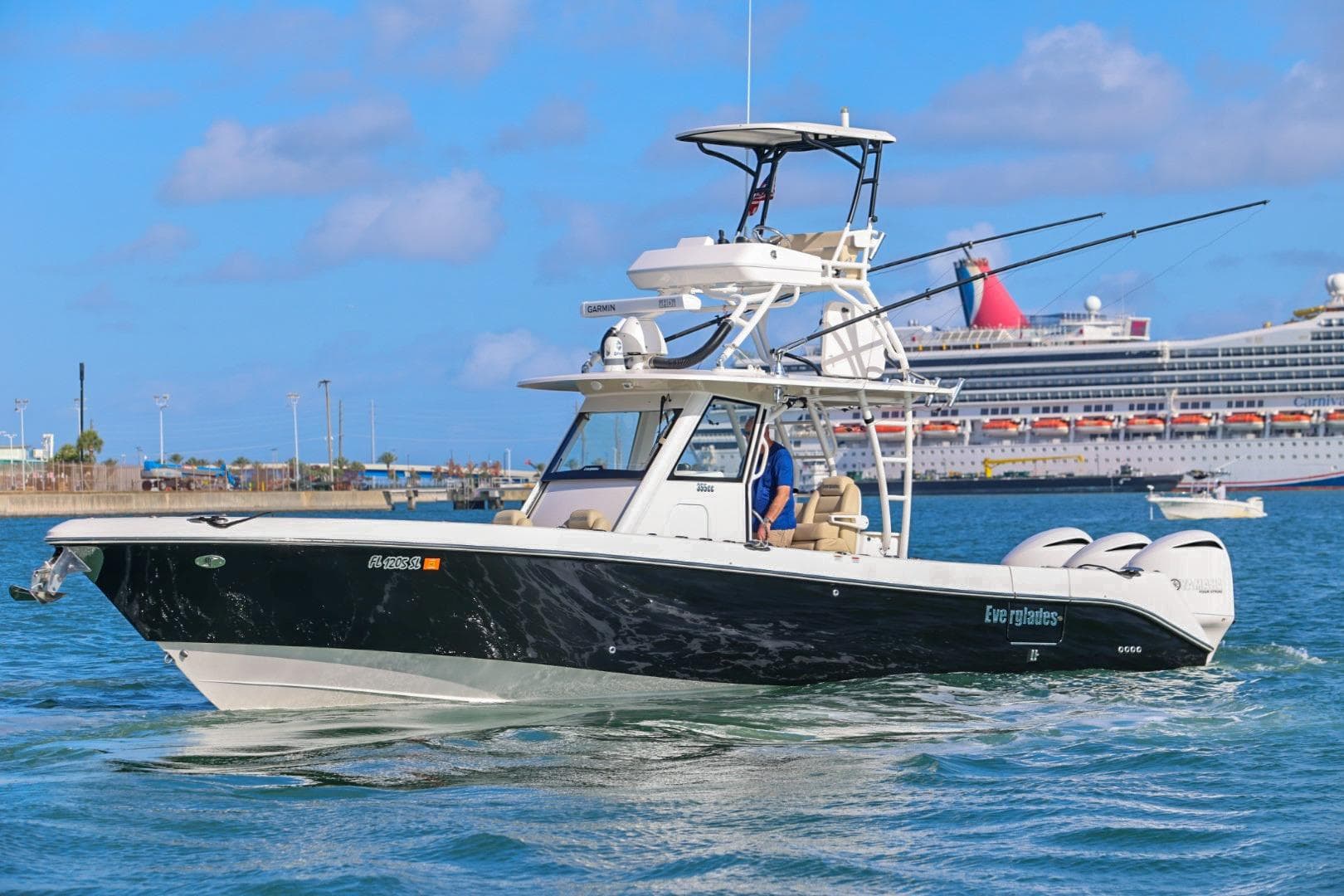 2017 Everglades 355 Center Console boat cruising in a harbor with a cruise ship in the background.
