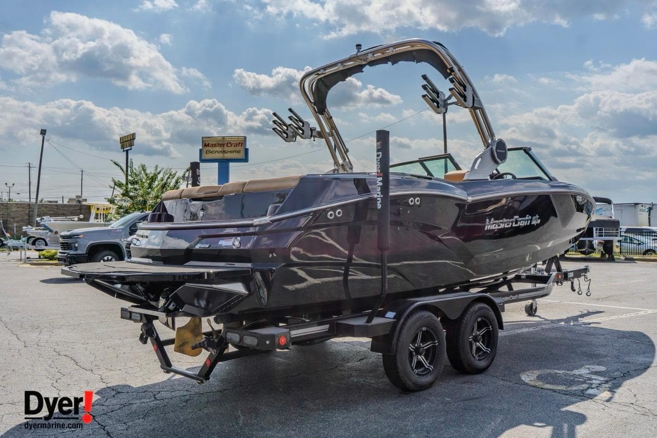 2026 MasterCraft NXT22 boat on trailer in parking lot under cloudy sky.