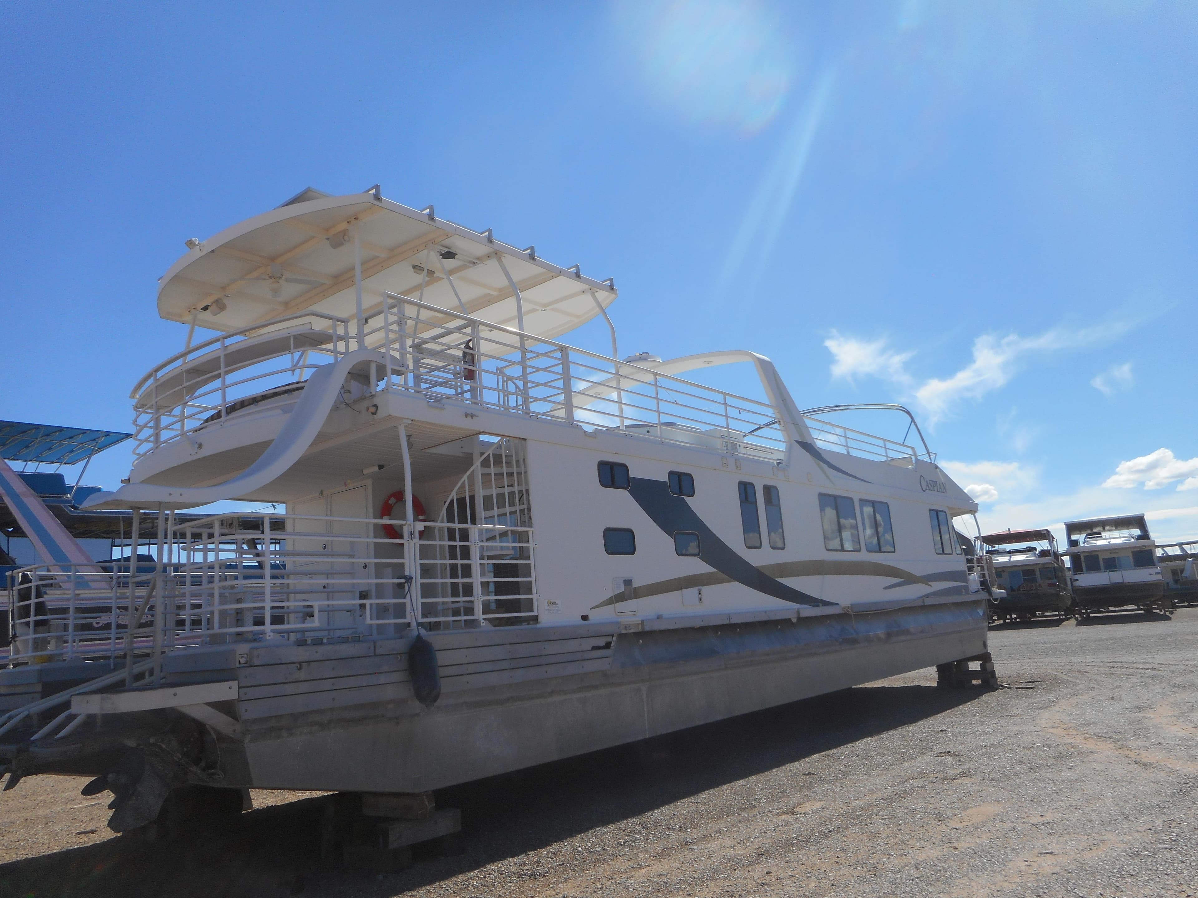 2005 Twin Anchors Caspian Share #9 houseboat on dry dock under a clear blue sky.