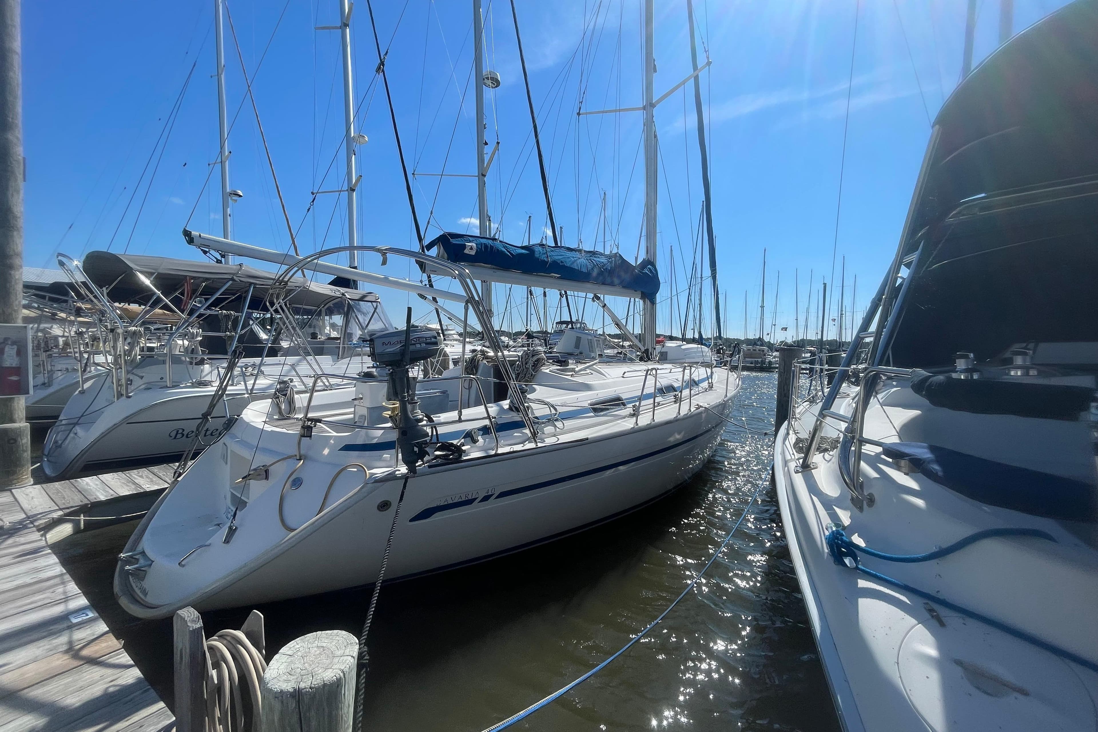 Sailboat Bavaria 40, 2002 model, docked at marina under clear blue sky.