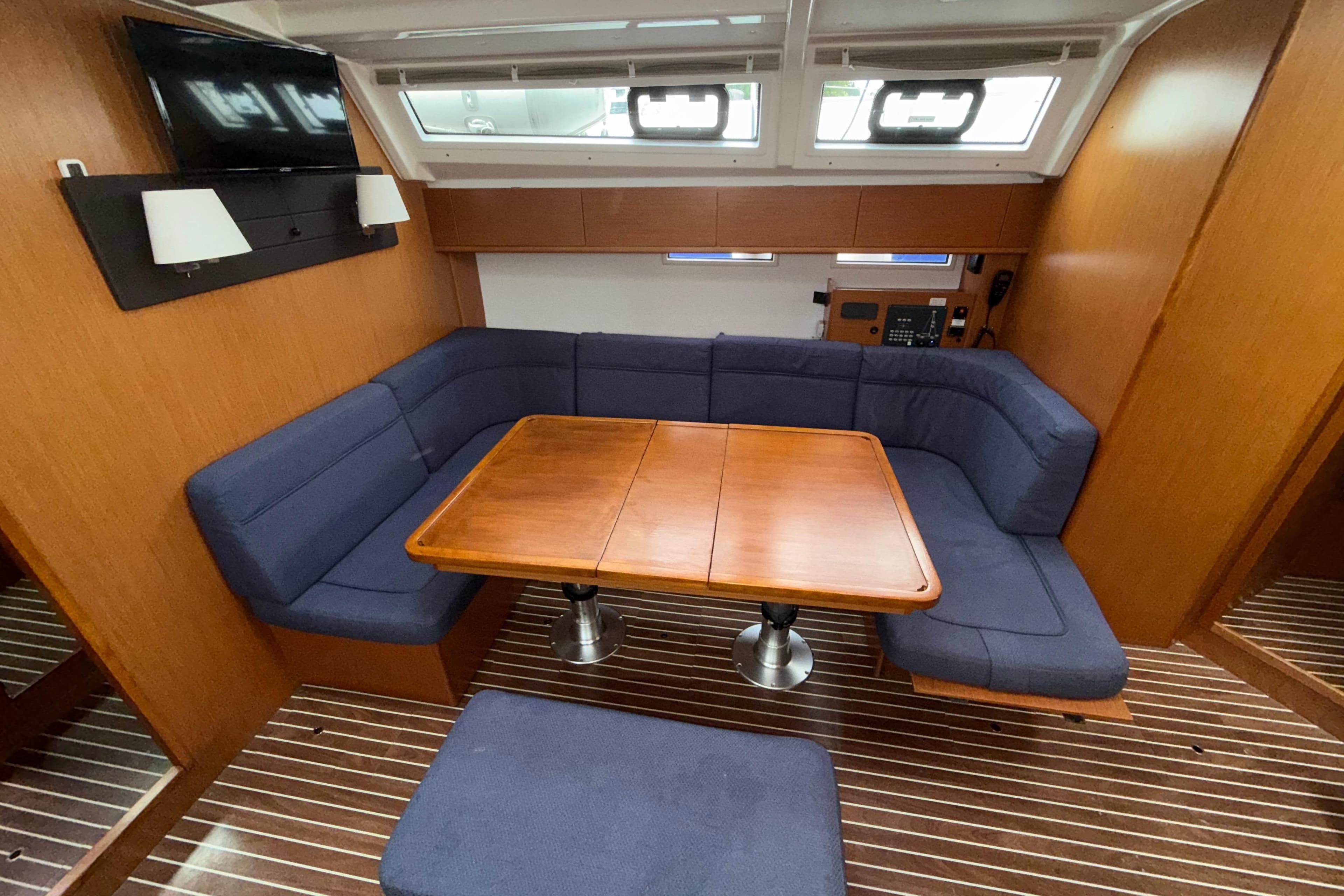 Interior of 2018 Bavaria 46 yacht with blue seating and wooden table.