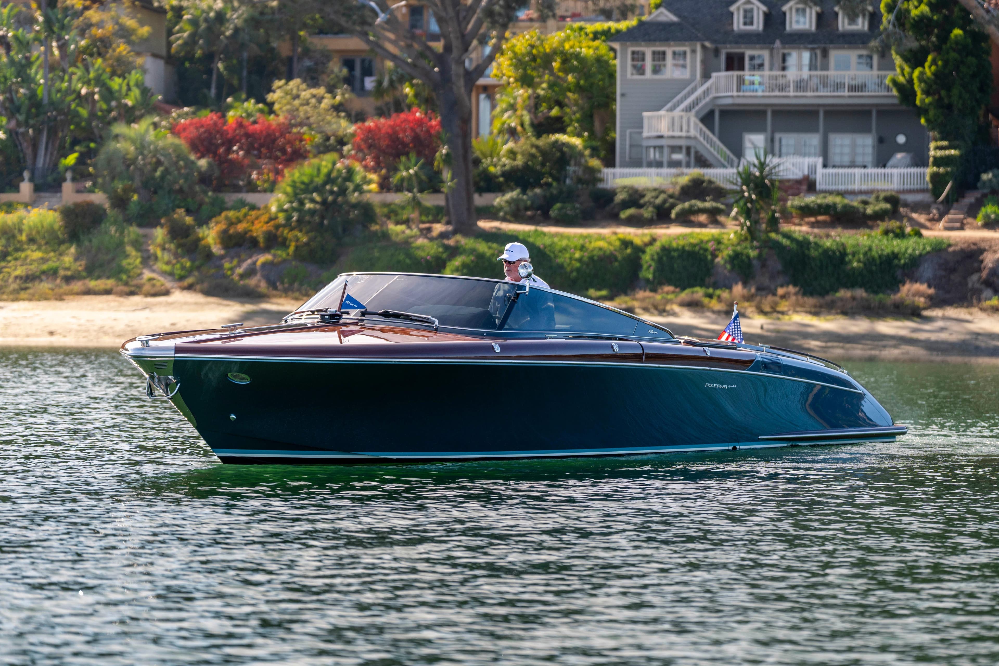 2026 Riva 33' Aquariva Special cruising on a serene lake with lush greenery.