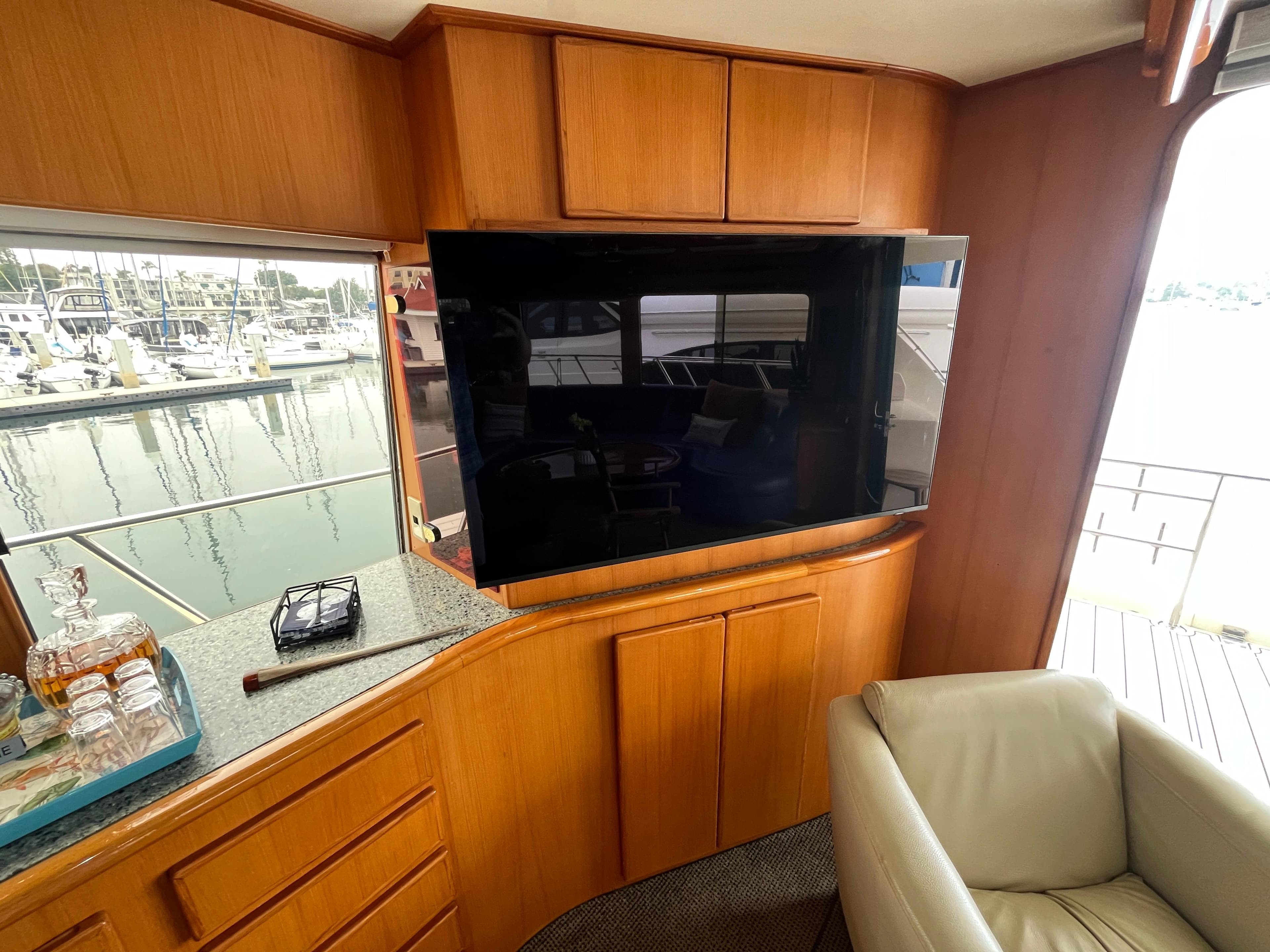 Interior of 1999 Mikelson Long-Range Luxury Sportfisher with TV, leather chair, and marina view.