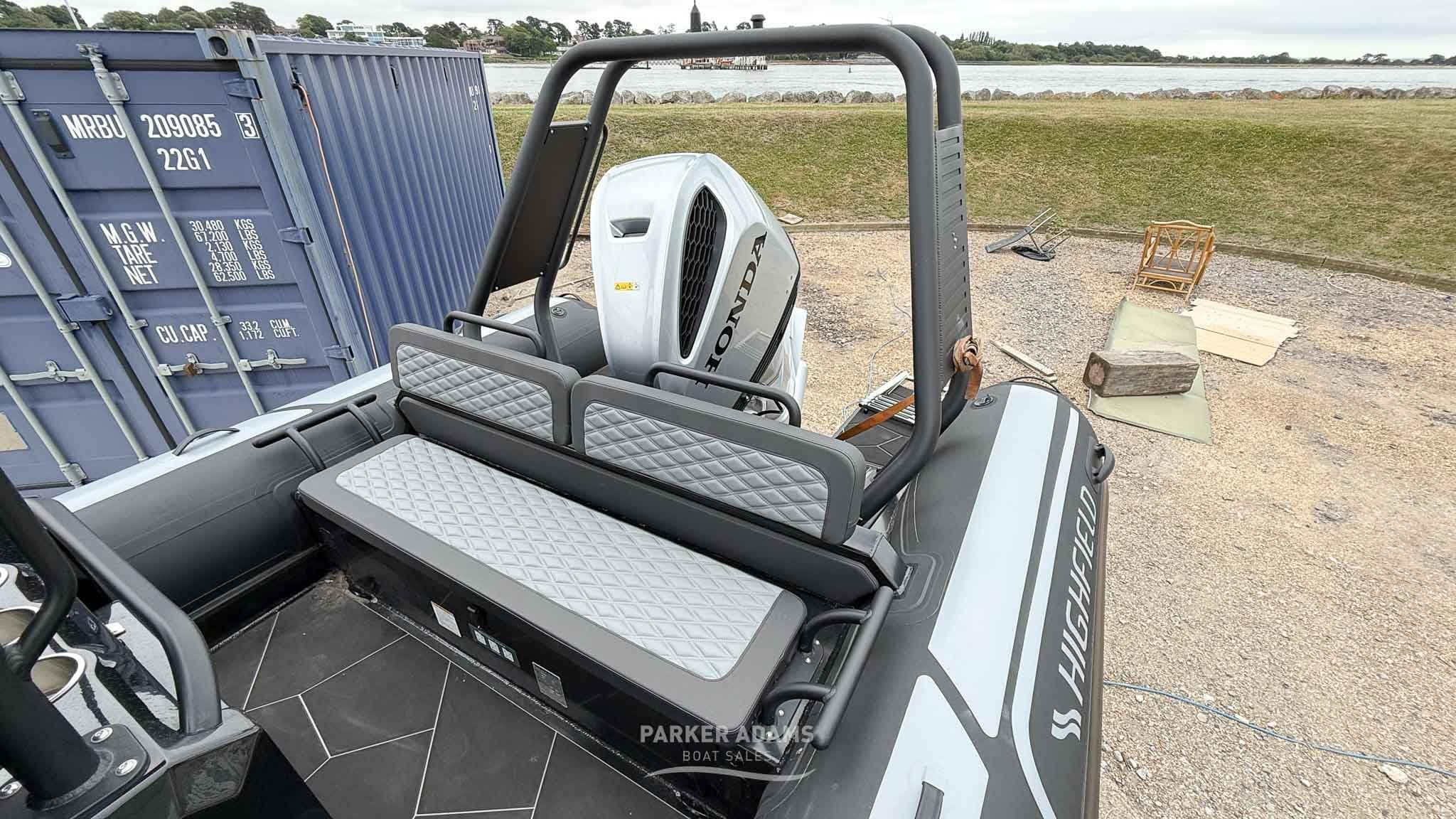 2025 Highfield Sport 700 boat with Honda engine, docked near a shipping container.
