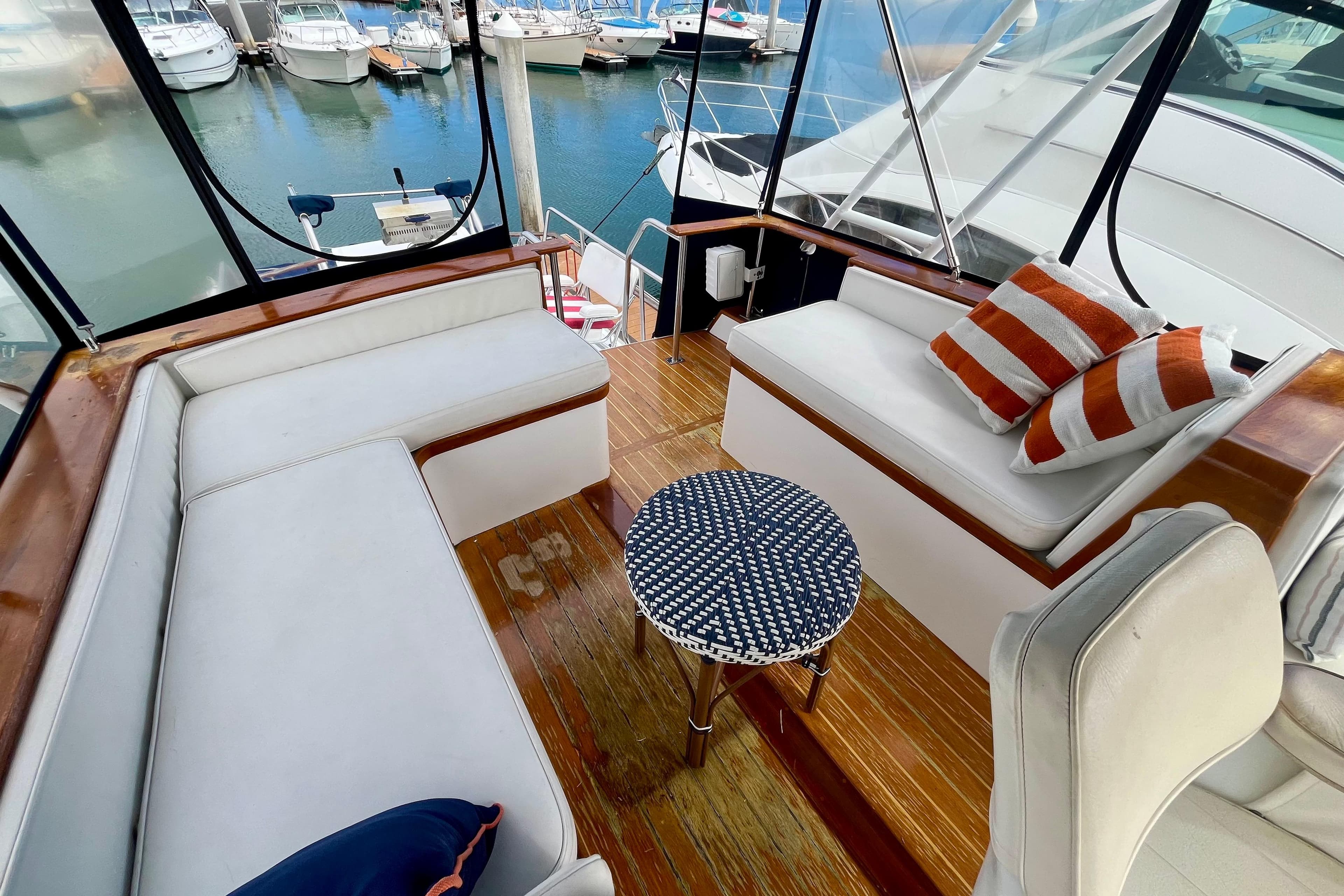 Interior of 1985 Monk 36 yacht with white seating, striped cushions, and marina view.