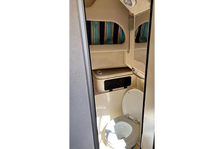 1999 Grady-White Marlin 300 boat bathroom interior with striped curtains and compact design.