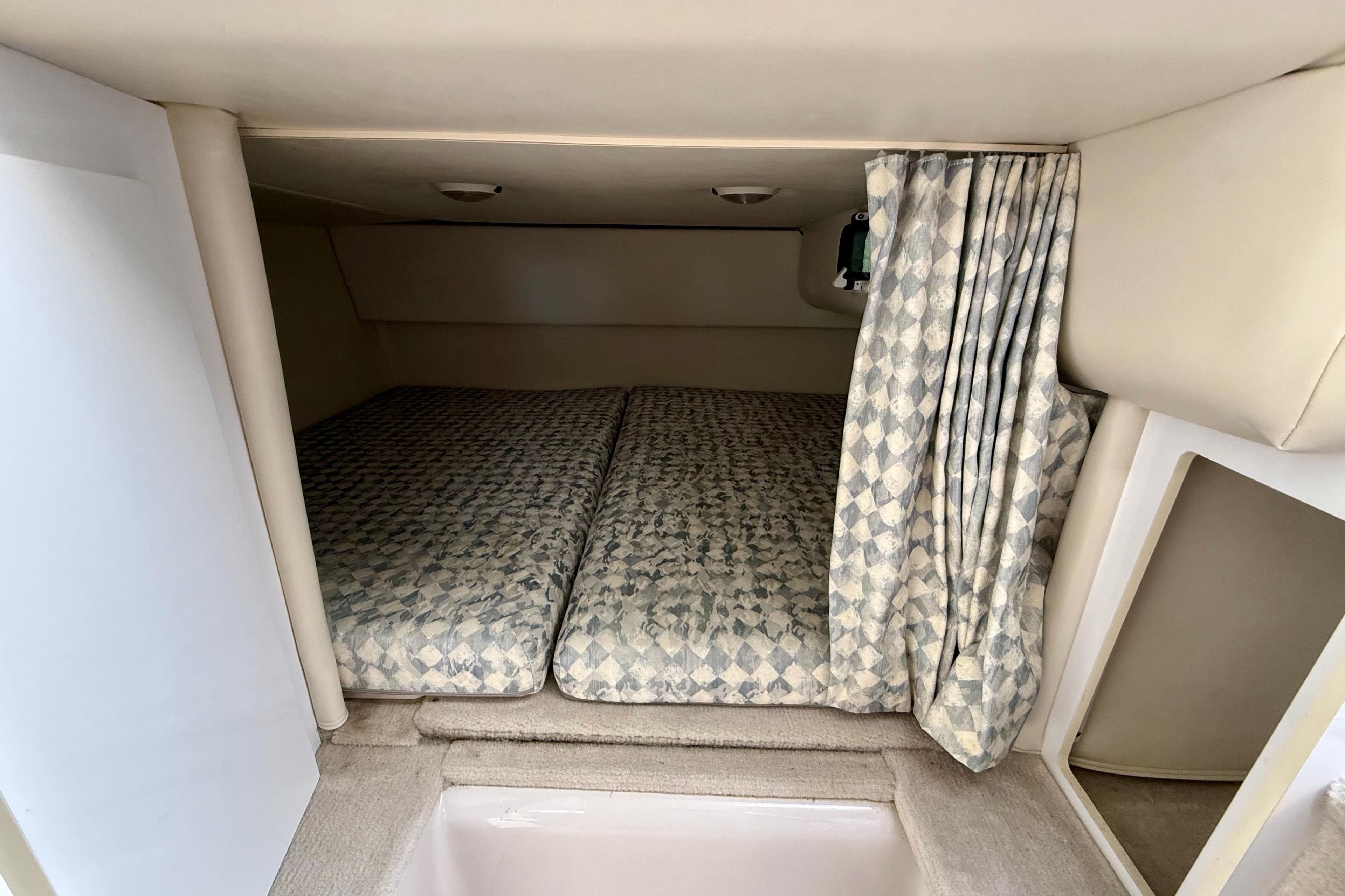 2000 Four Winns 288 Vista cabin interior with patterned bedding and privacy curtain.