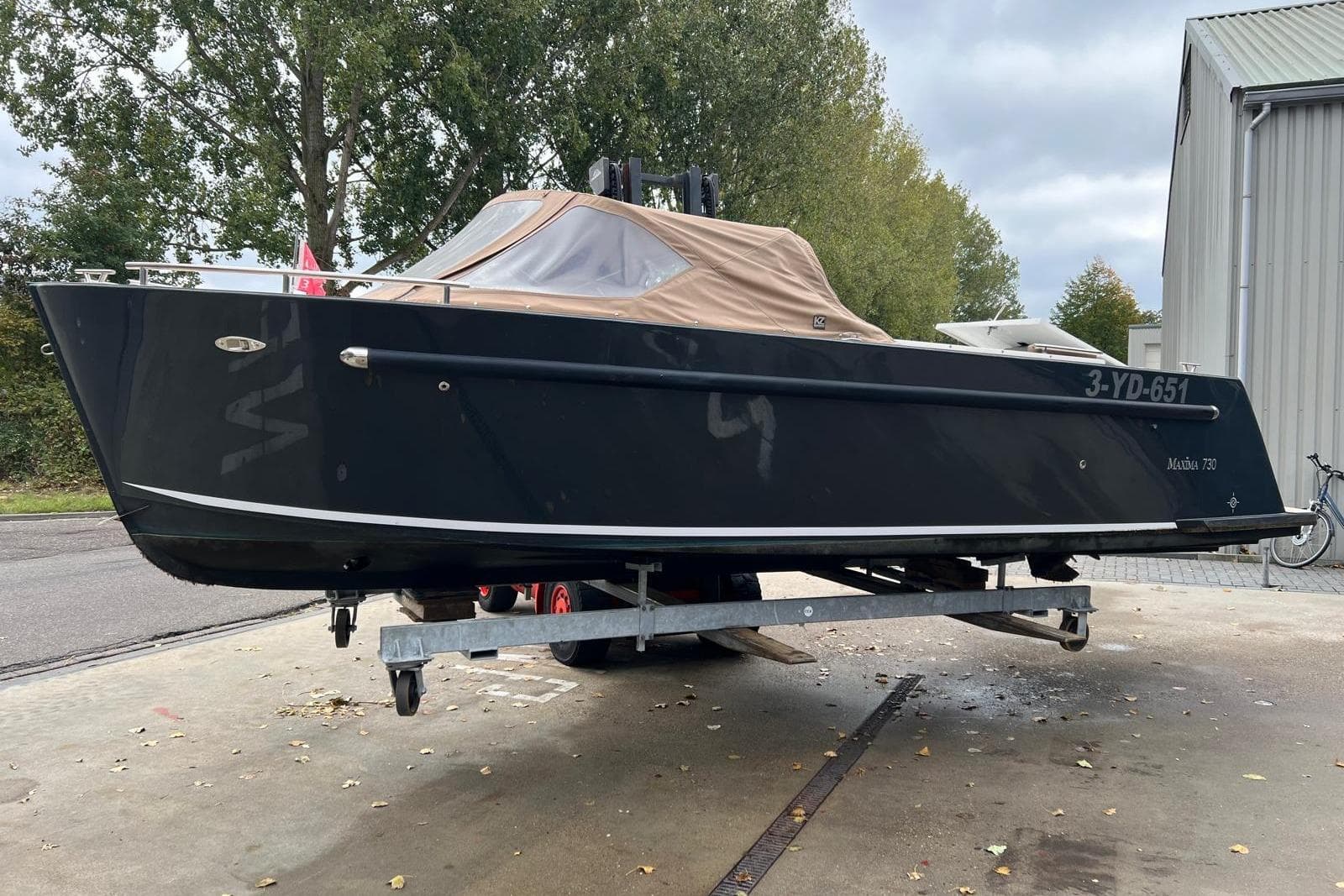 2020 Maxima 730 boat on trailer, black hull, beige canopy, outdoor setting.
