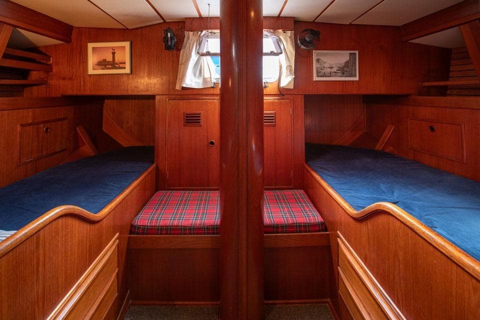 Interior of 1983 Nautor Swan 65 yacht with wooden bunks and nautical decor.