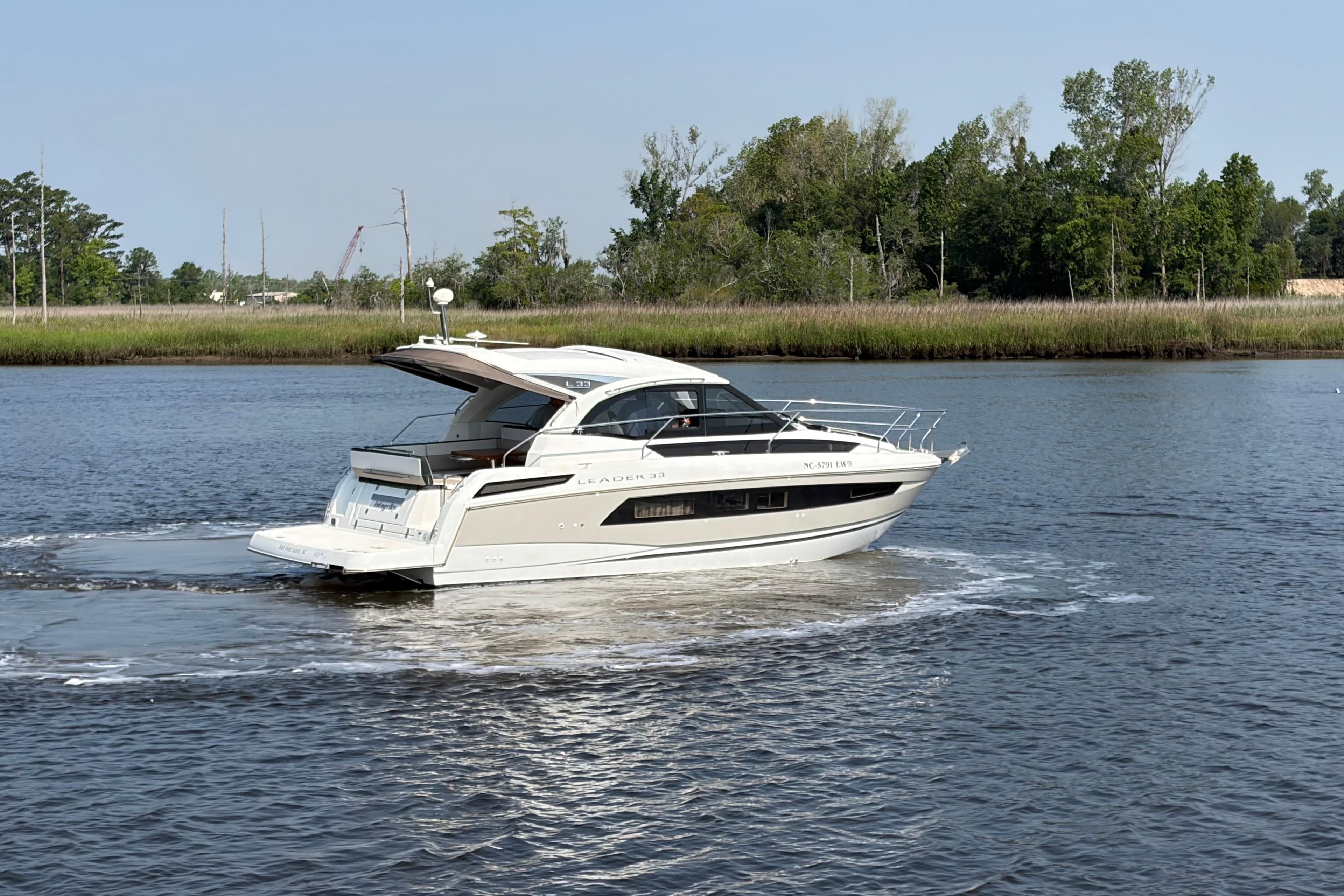 2018 Jeanneau Leader 33 cruising on a calm river with lush greenery in the background.
