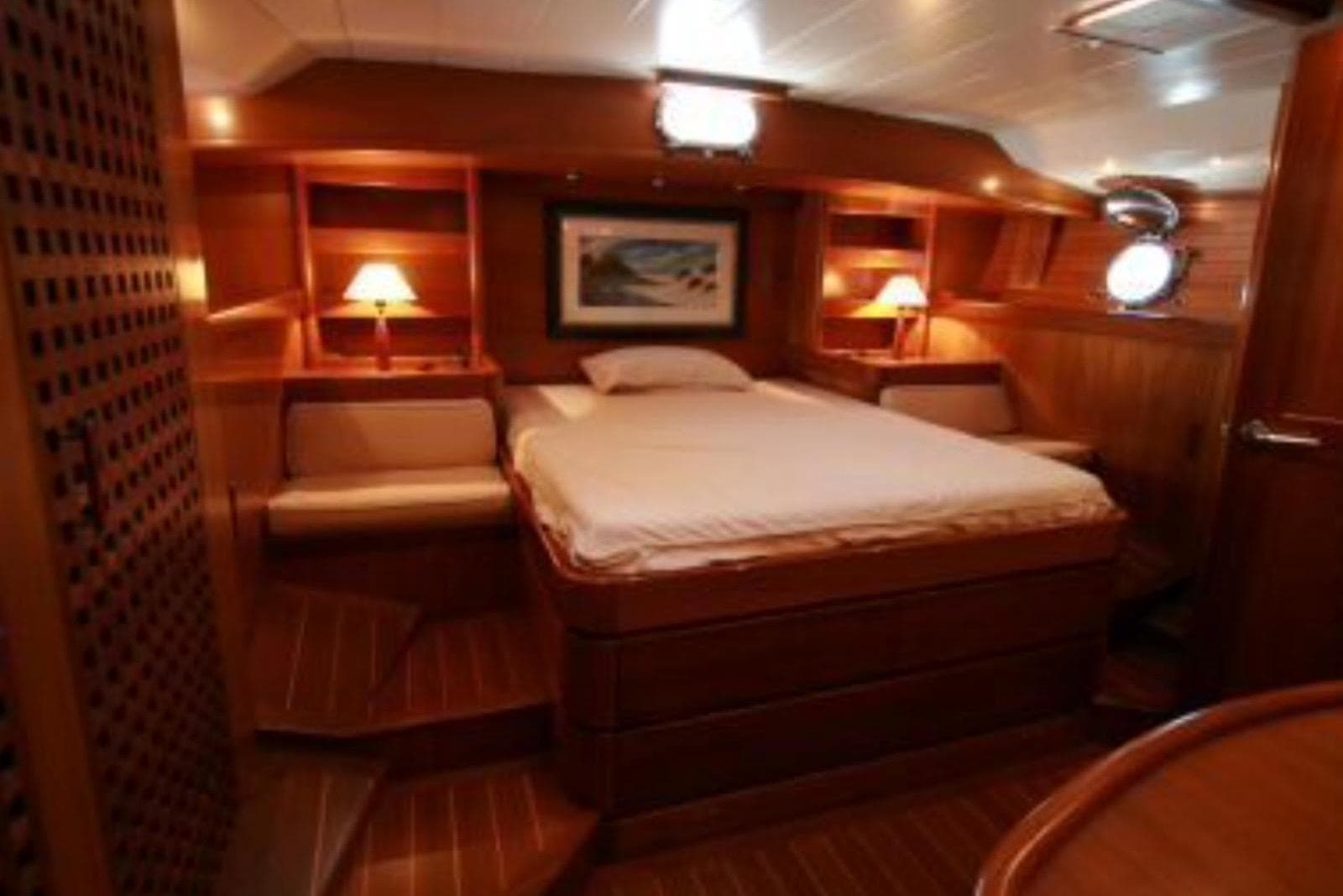 Luxurious wooden cabin interior of 2000 MB92 25M yacht with cozy bed and ambient lighting.