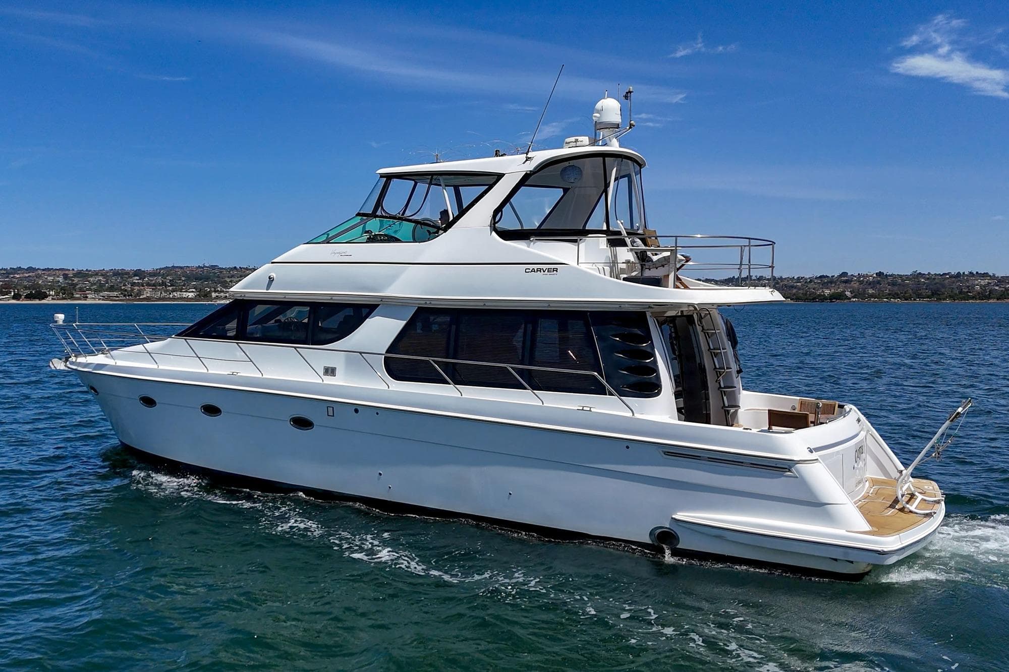 2003 Carver 530 Voyager Pilothouse yacht cruising on open water under clear skies.