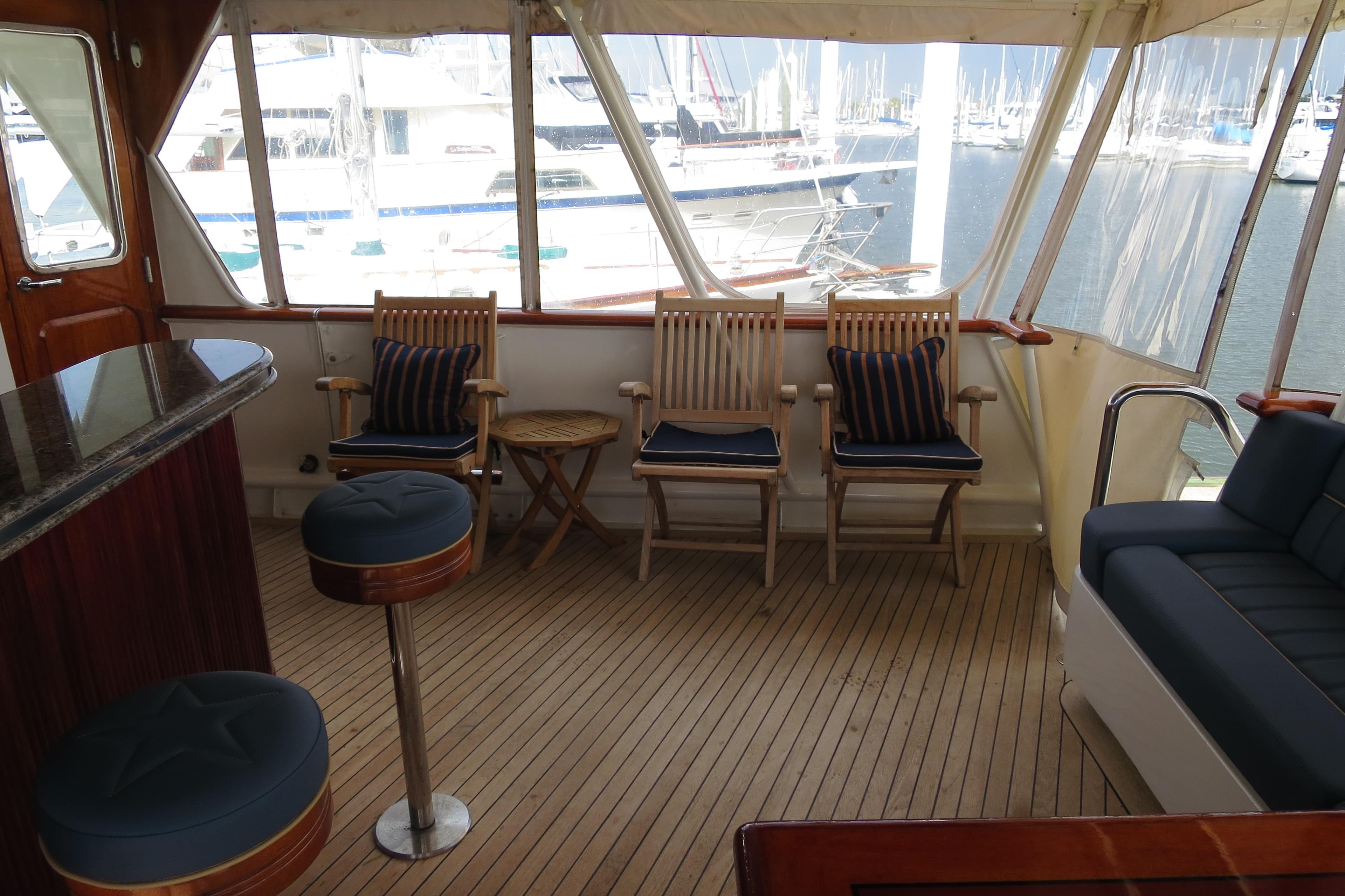 1964 Striker Cockpit interior with wooden flooring, bar stools, and marina view.