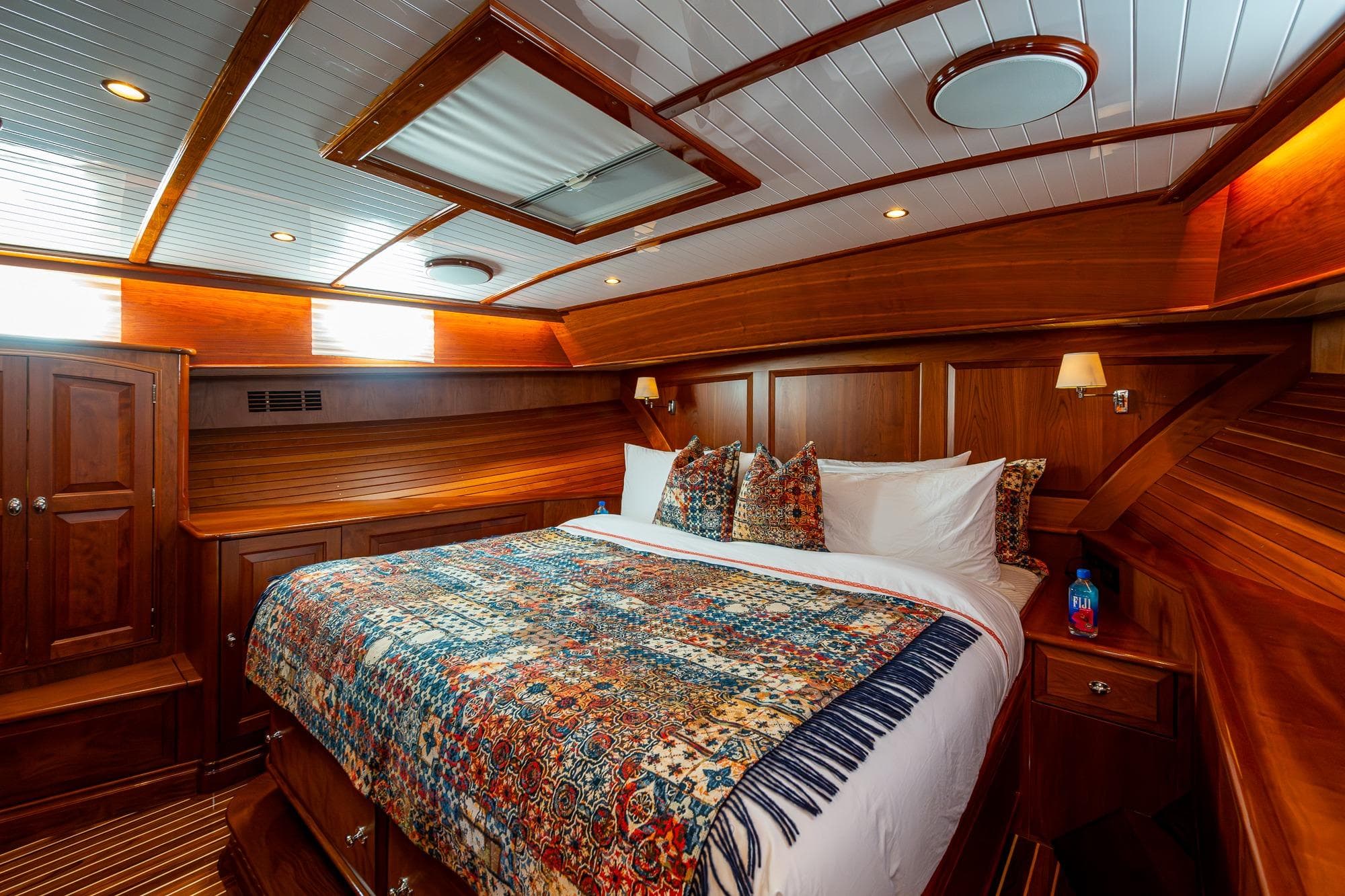 Luxurious 2021 Hinckley Talaria yacht cabin with elegant wood paneling and cozy bedding.