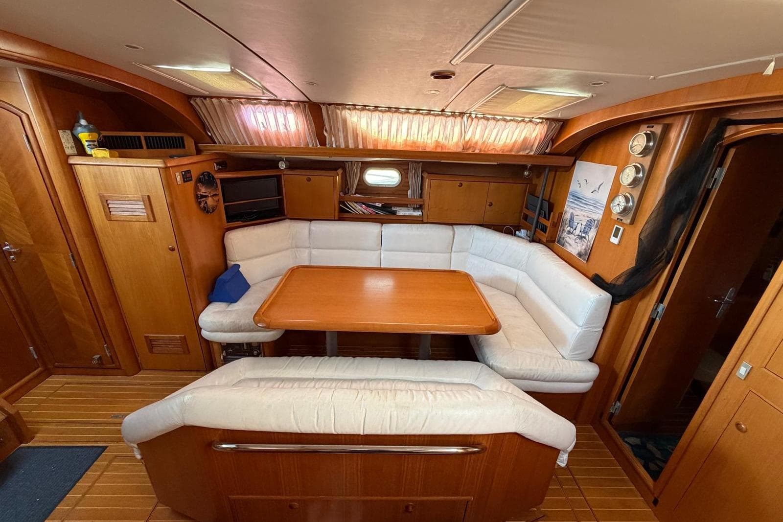 Interior of 2000 Jeanneau Sun Odyssey 52.2 yacht with wooden furnishings and white seating.