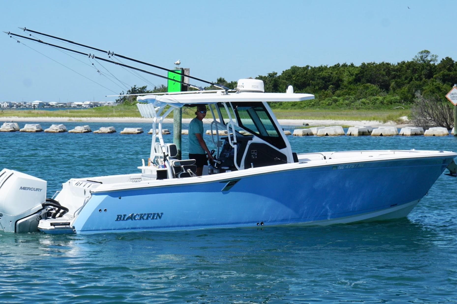 2024 Blackfin 272 CC boat cruising on a sunny day with fishing rods.