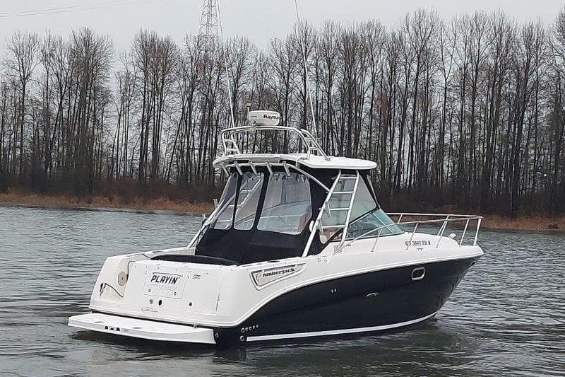 2009 Sea Ray 290 Amberjack boat on a calm river with trees in the background.