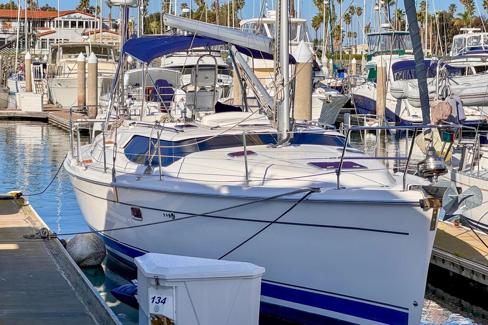 2009 Hunter 45 Center Cockpit yacht docked in a marina, surrounded by other boats.