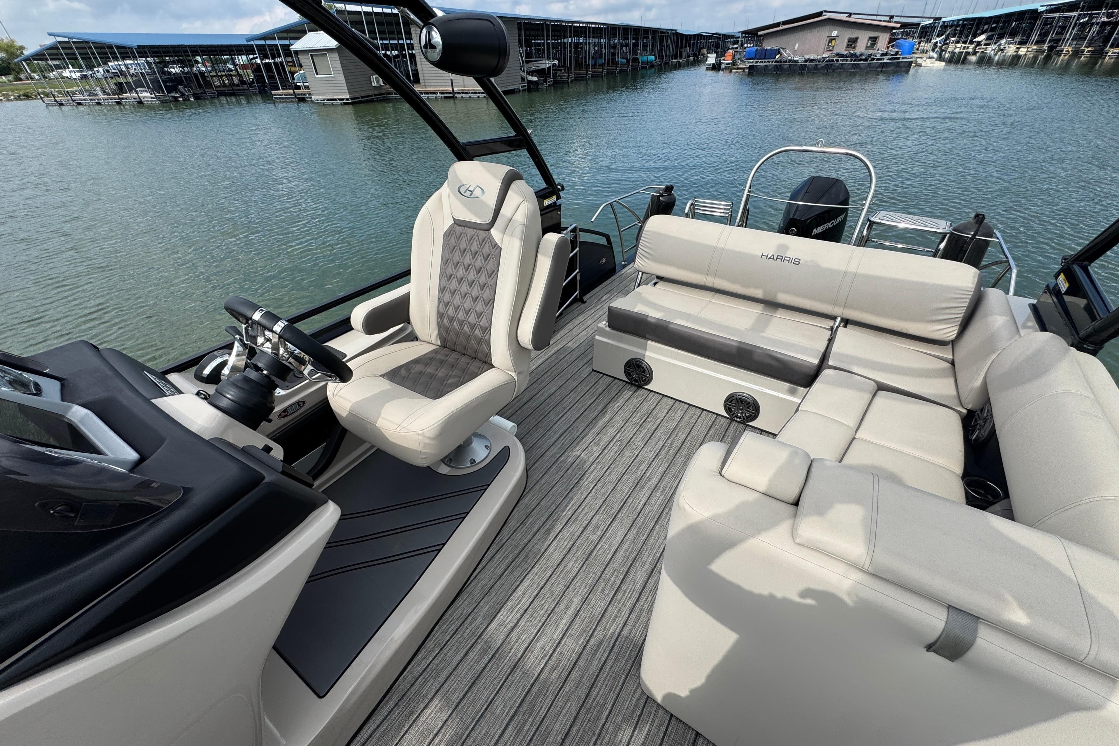 2021 Harris Solstice 230 pontoon boat interior with luxurious seating and helm, docked by the water.