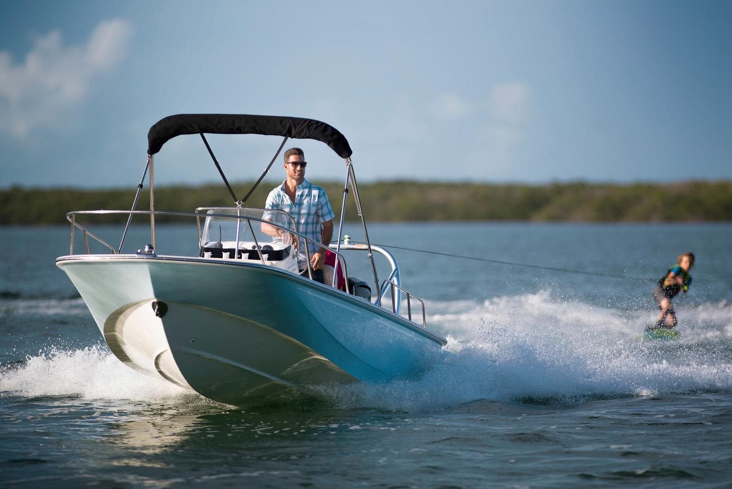 Manufacturer Provided Image: 2026 Boston Whaler 170 Montauk boat towing a wakeboarder on a sunny day.