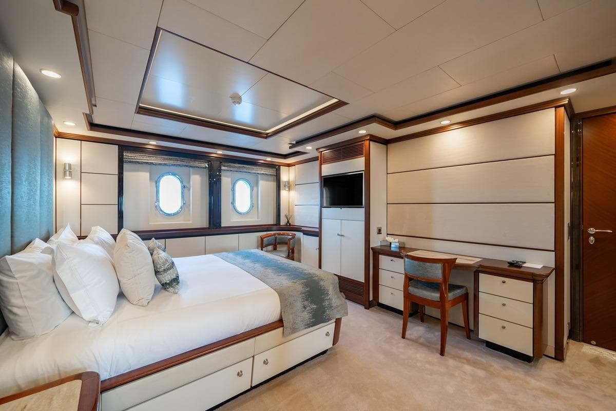 Luxurious yacht bedroom interior on CRN Magnifica, 2001 model, featuring elegant furnishings and porthole windows.