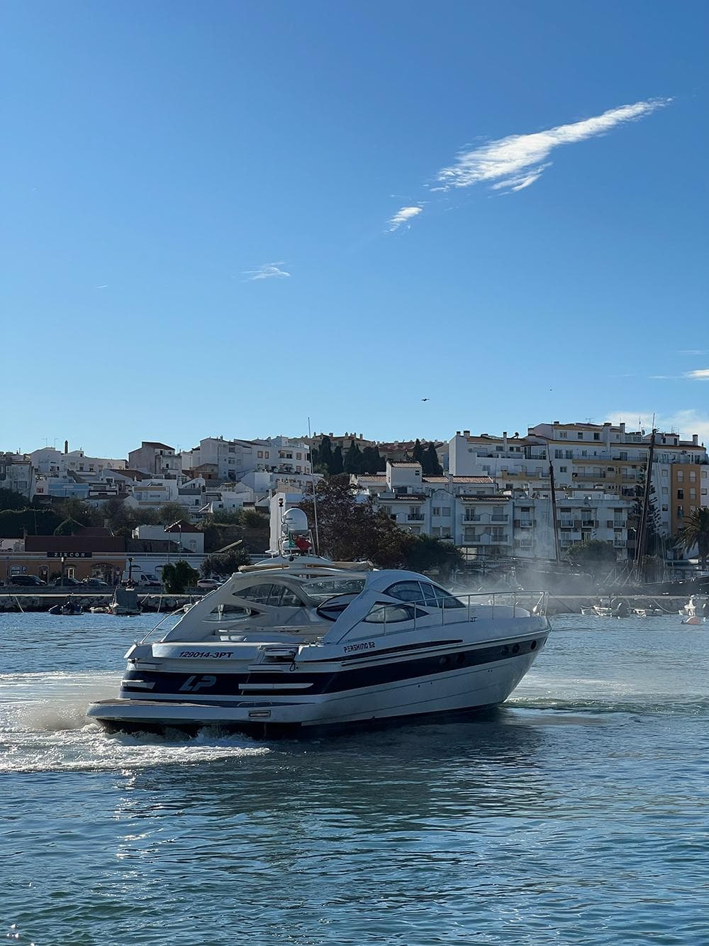 2001 Pershing 52 yacht cruising on a sunny day near coastal buildings.