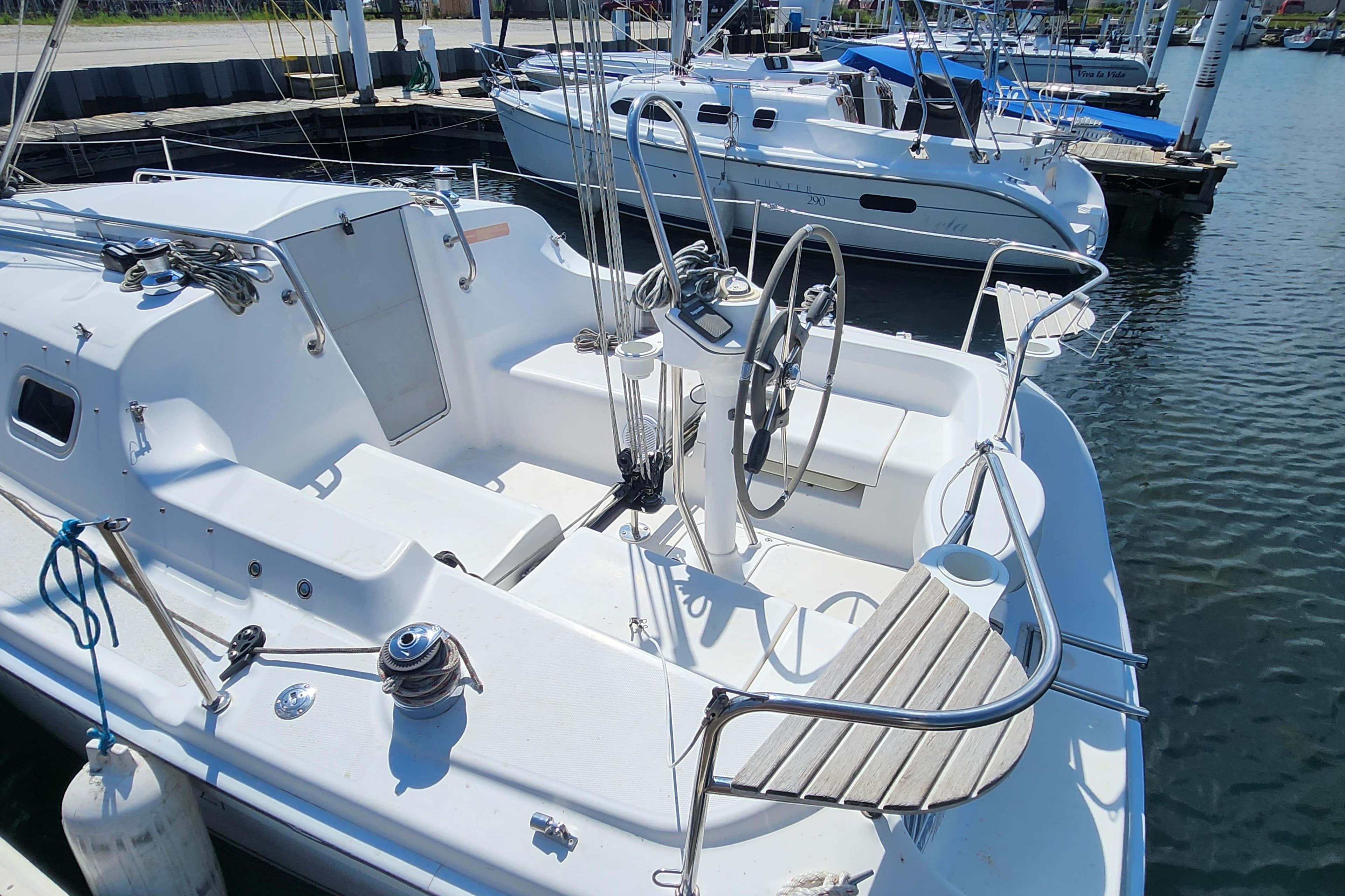 2005 Hunter 27 sailboat docked at marina, featuring spacious cockpit and steering wheel.