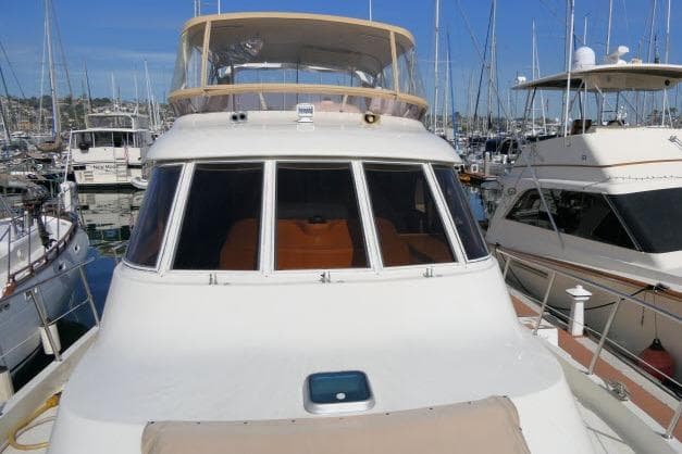 1999 Hampton 490 Pilothouse yacht docked in a marina, surrounded by other boats.