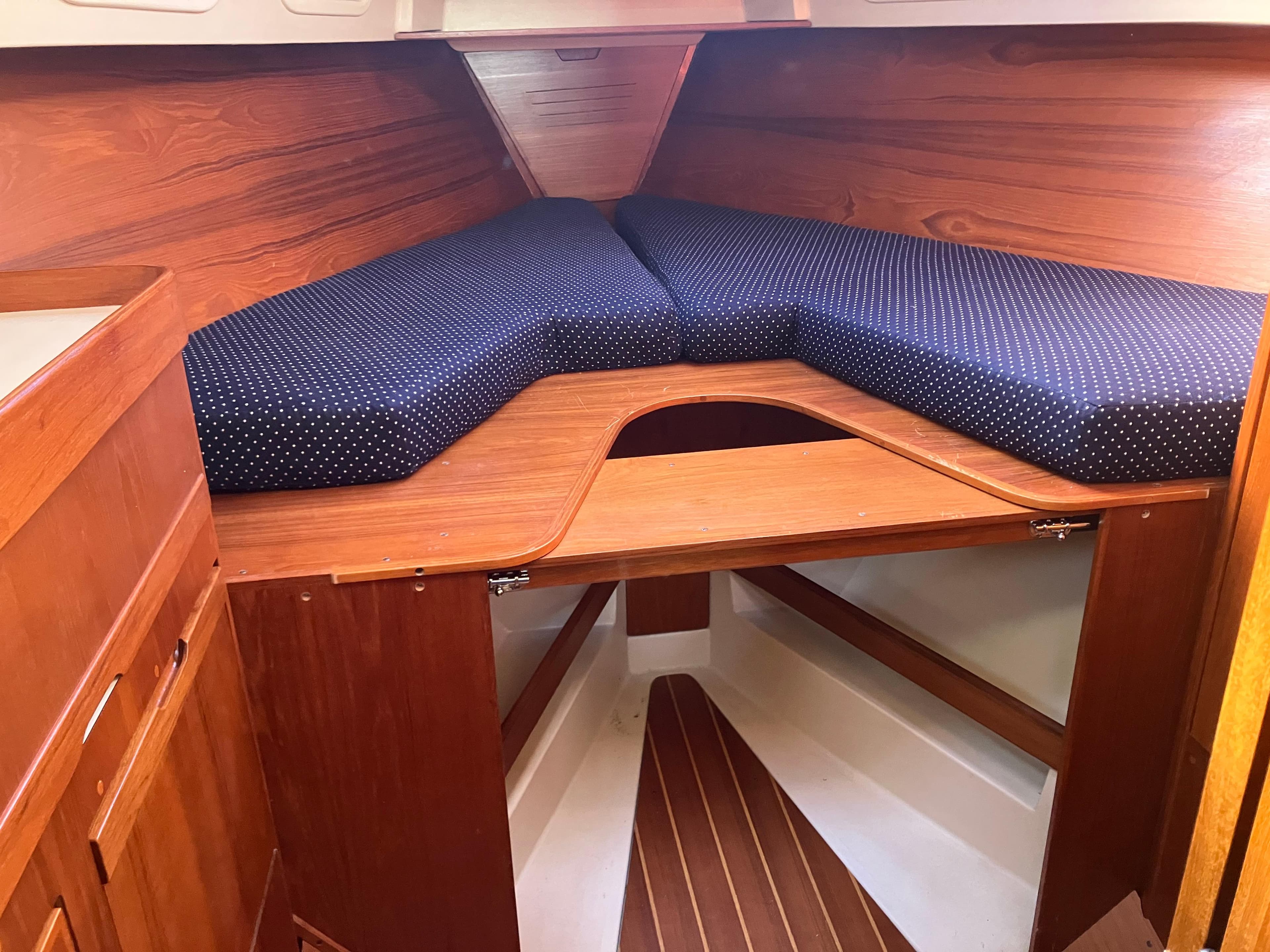 Cozy cabin interior of 1989 Pearson 39-2 sailboat with wooden finish and blue cushions.