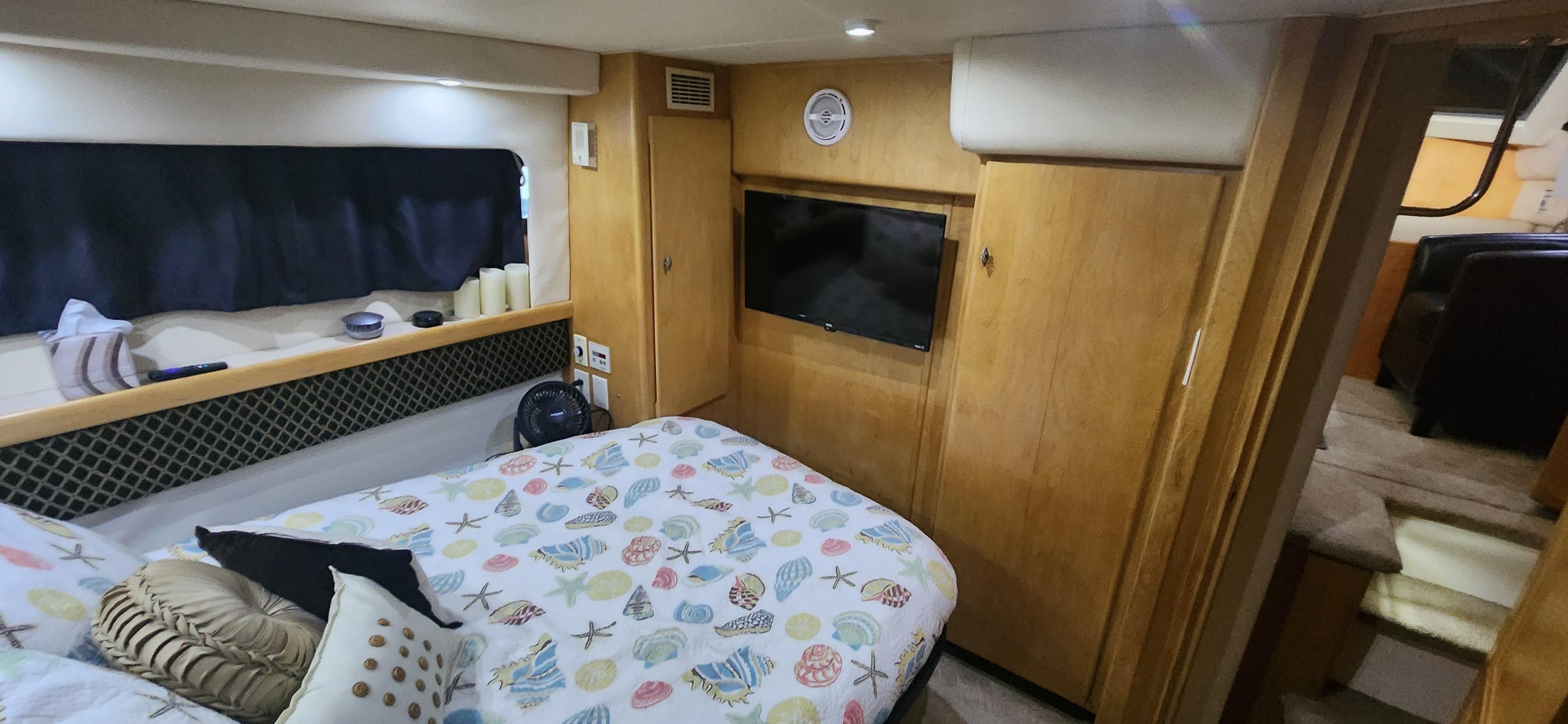 Interior of 1996 Carver 400 Cockpit Motor Yacht bedroom with cozy decor and TV.
