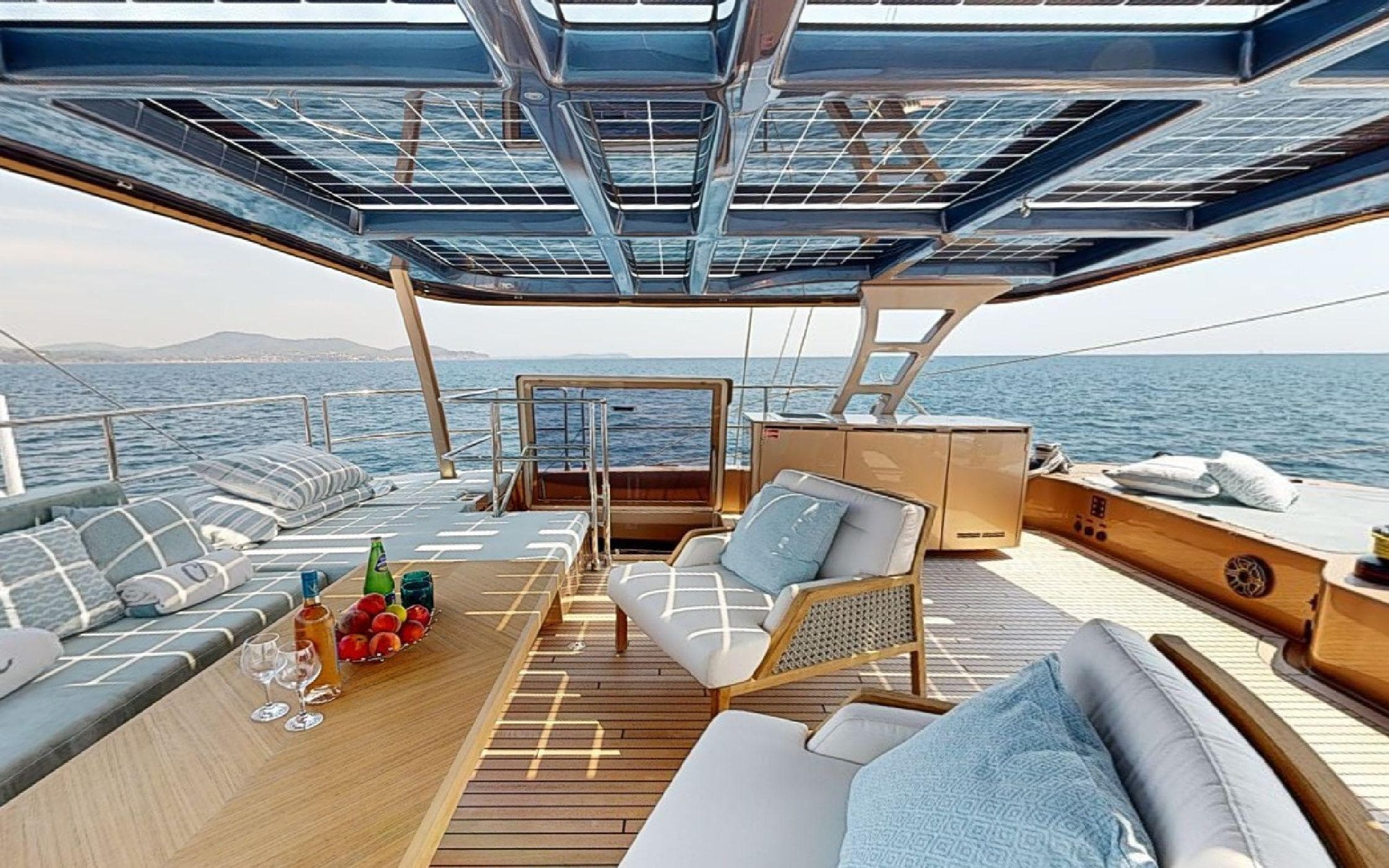 Luxurious Sunreef 60 Sail yacht deck with elegant seating, ocean view, and refreshments, 2024 model.