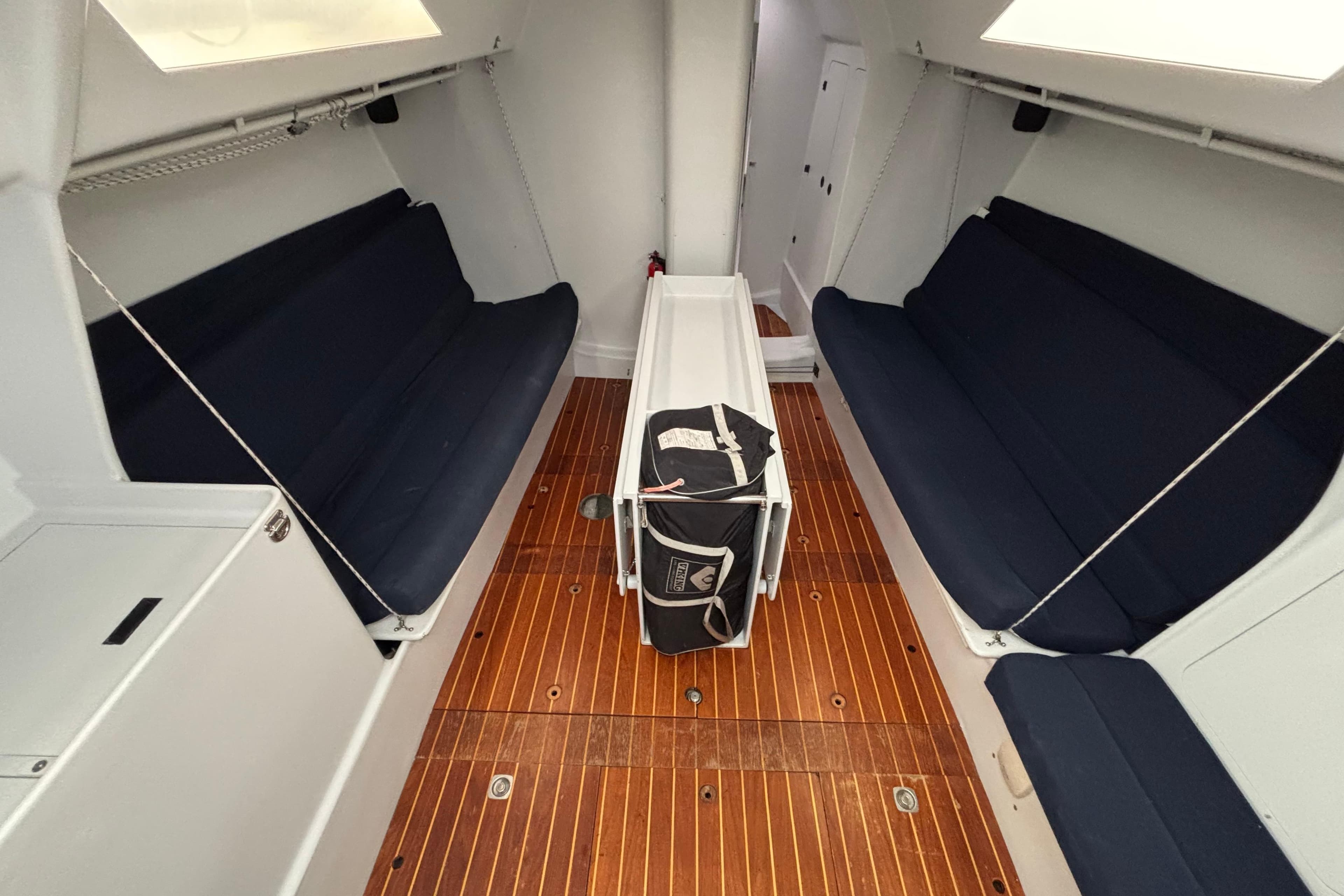 Interior of a 1995 Tripp 47 sailboat with wooden flooring and navy seating.