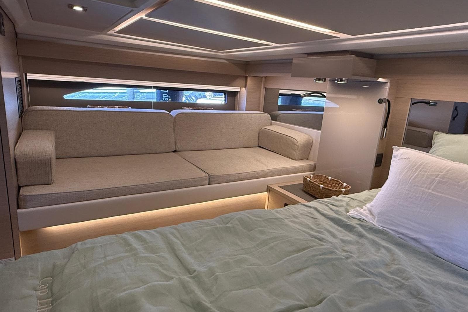 Luxurious interior of 2023 Jeanneau DB/43 IB yacht with cozy seating and elegant bedding.