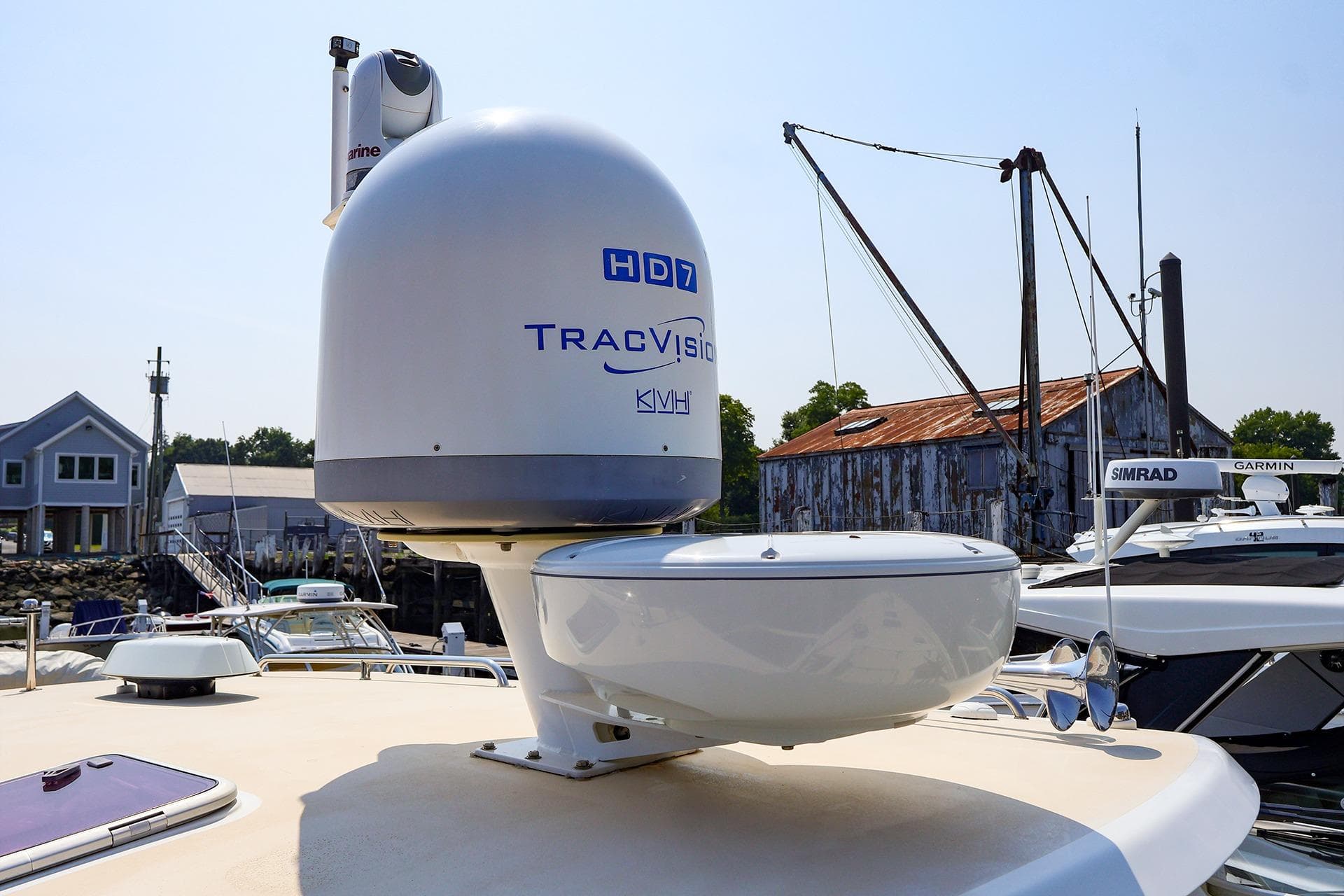 Satellite equipment on 2010 MJM 40z Downeast yacht, docked near rustic buildings.