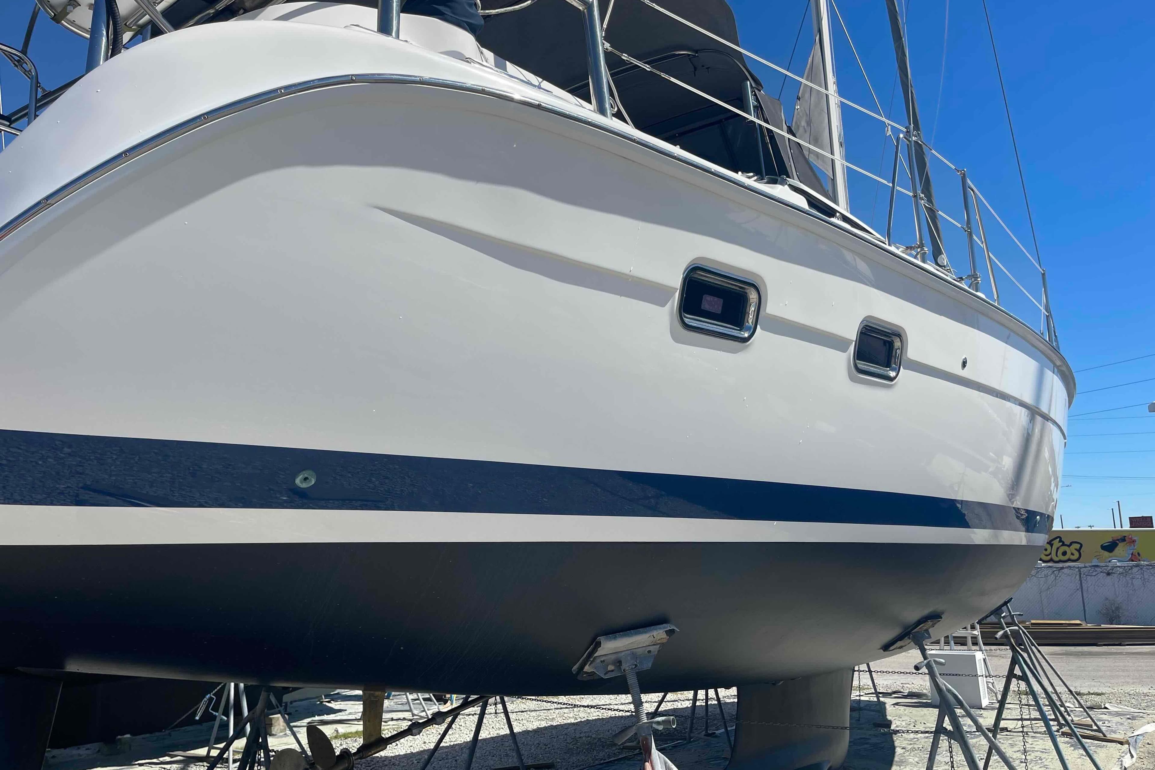 2003 Hunter 426 Deck Salon sailboat on dry dock, side view under clear blue sky.
