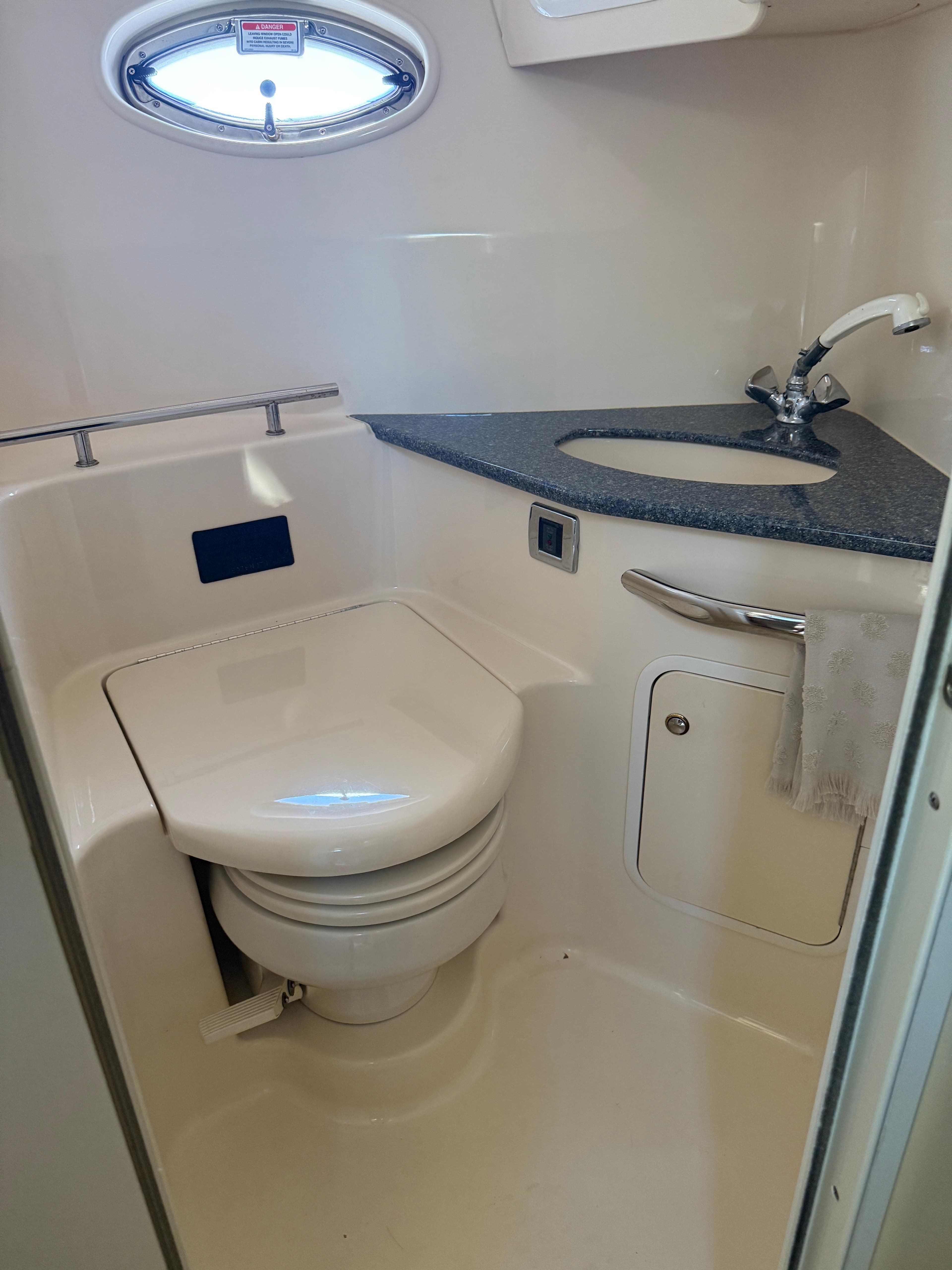 2003 Sea Ray 420 Sundancer bathroom with toilet, sink, and porthole window.