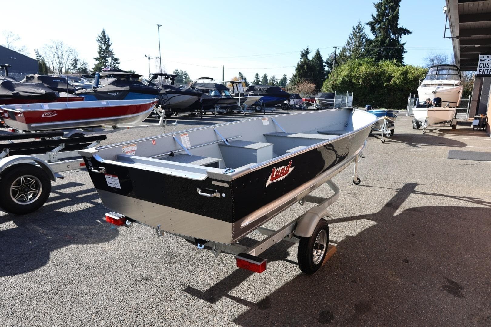 2026 Lund SSV-16 Tiller boat on trailer in outdoor showroom.