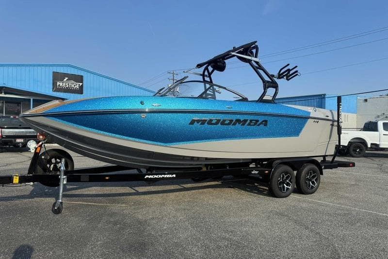 2026 Moomba Mojo boat in vibrant blue on a trailer at a dealership.
