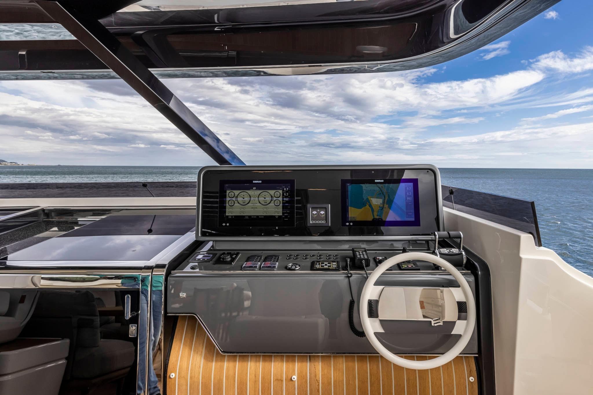 Helm of 2023 Ferretti Yachts 1000 with modern navigation displays and ocean view.