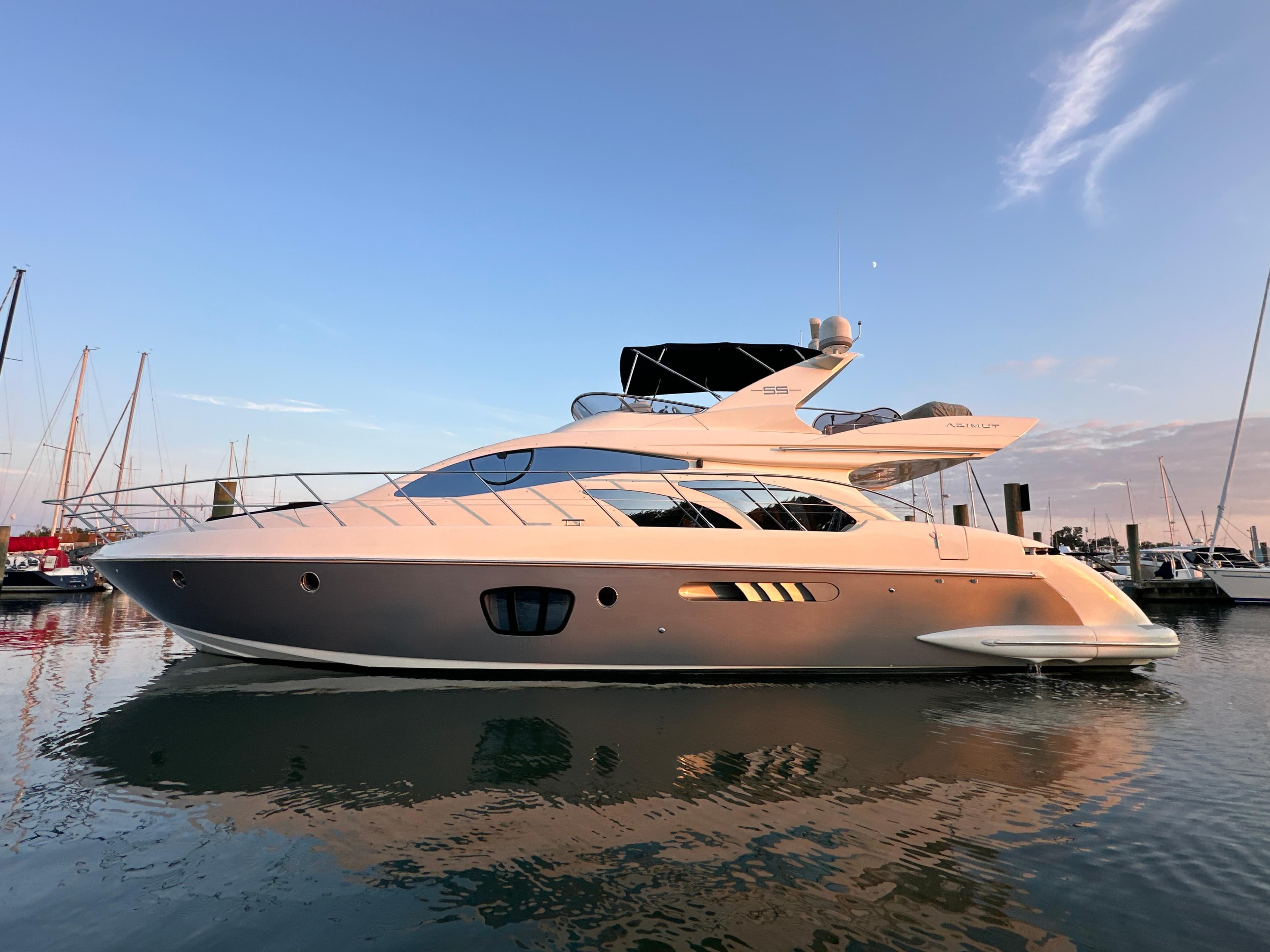 Luxury 2010 Azimut 55E yacht docked at sunset, reflecting on calm water.