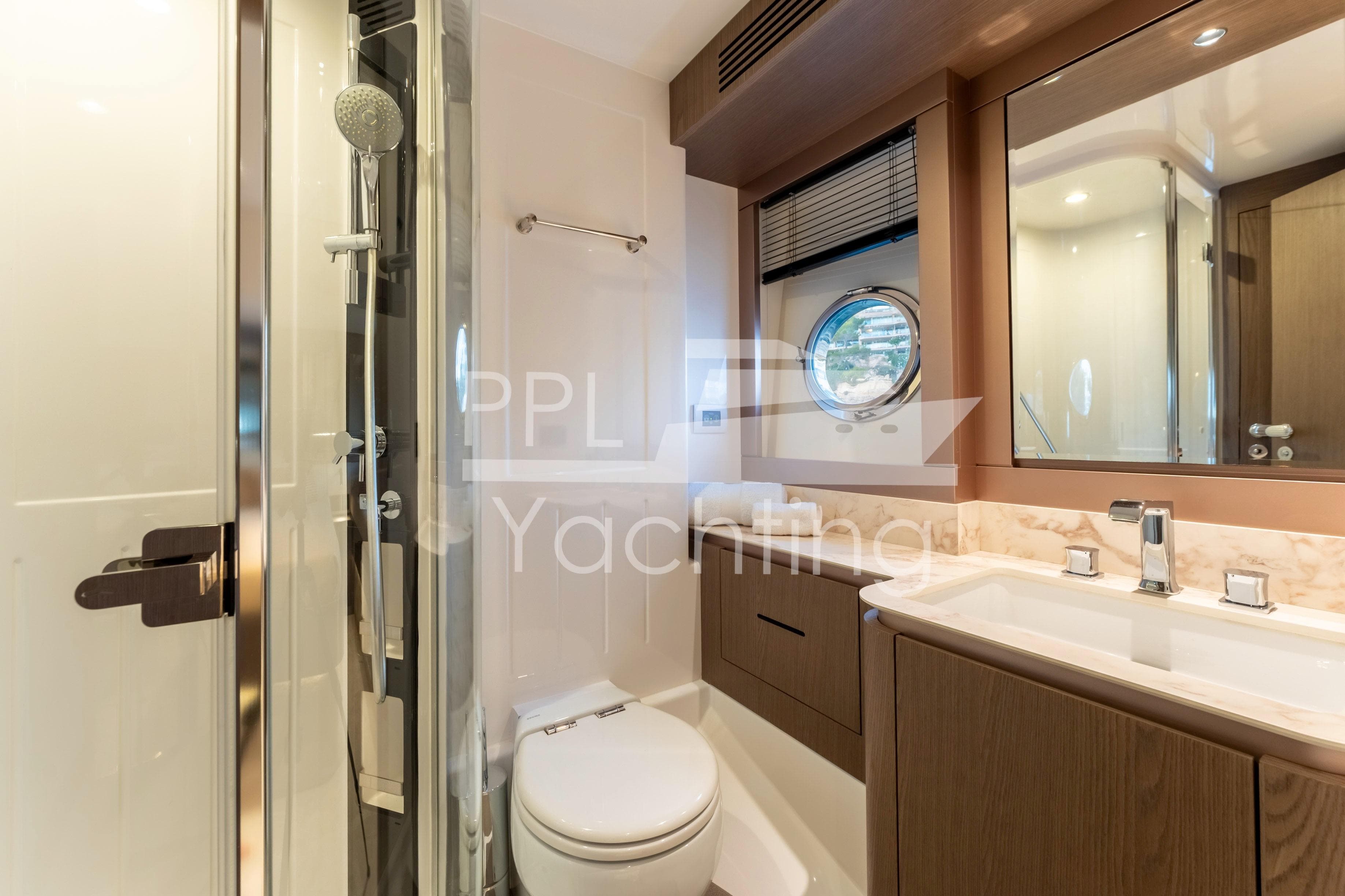 Luxurious bathroom in 2021 Azimut Magellano 66 yacht with modern fixtures and porthole window.