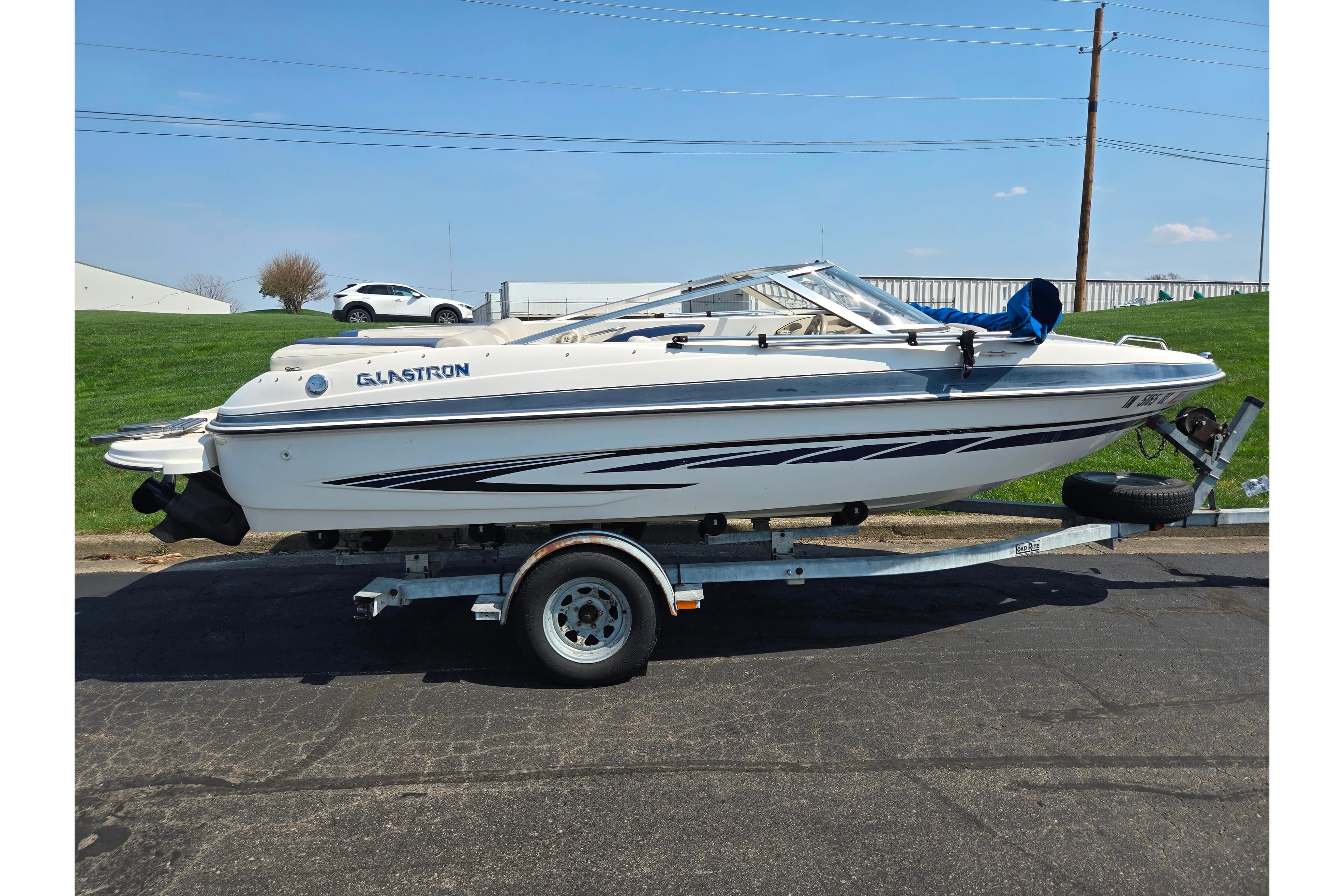 2007 Glastron GT 185 boat on trailer, parked outdoors on a sunny day.