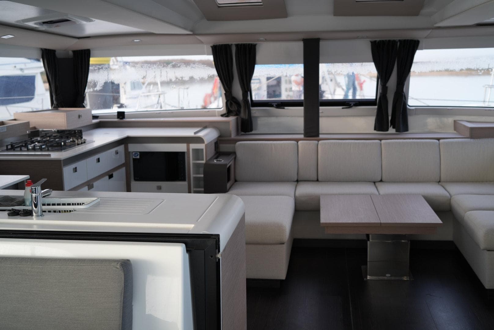 Luxurious interior of 2022 Fountaine Pajot Elba Quatour catamaran with modern kitchen and seating area.